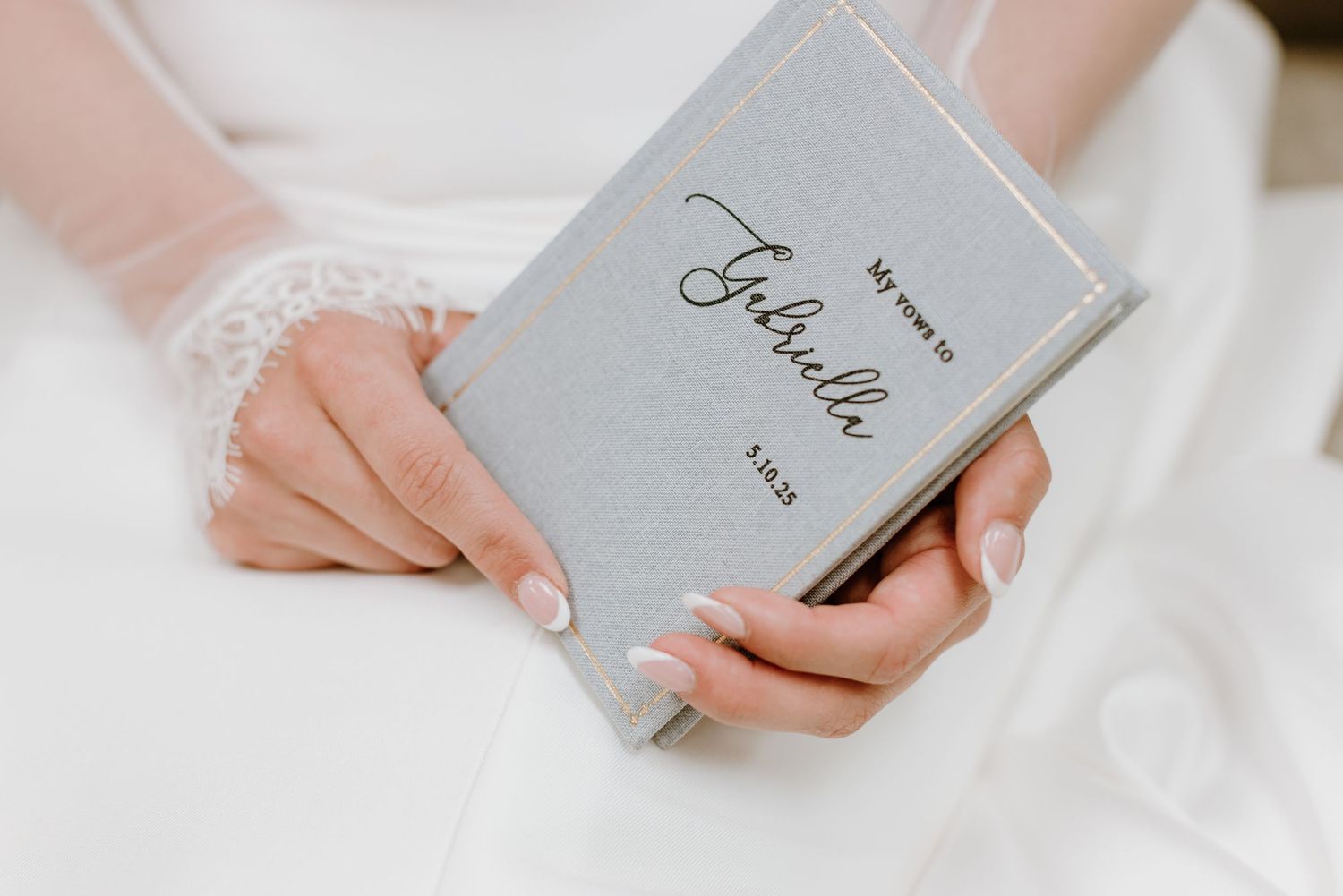 Someone wearing a white dress holds a small gray book with 'Faith' written on the cover.