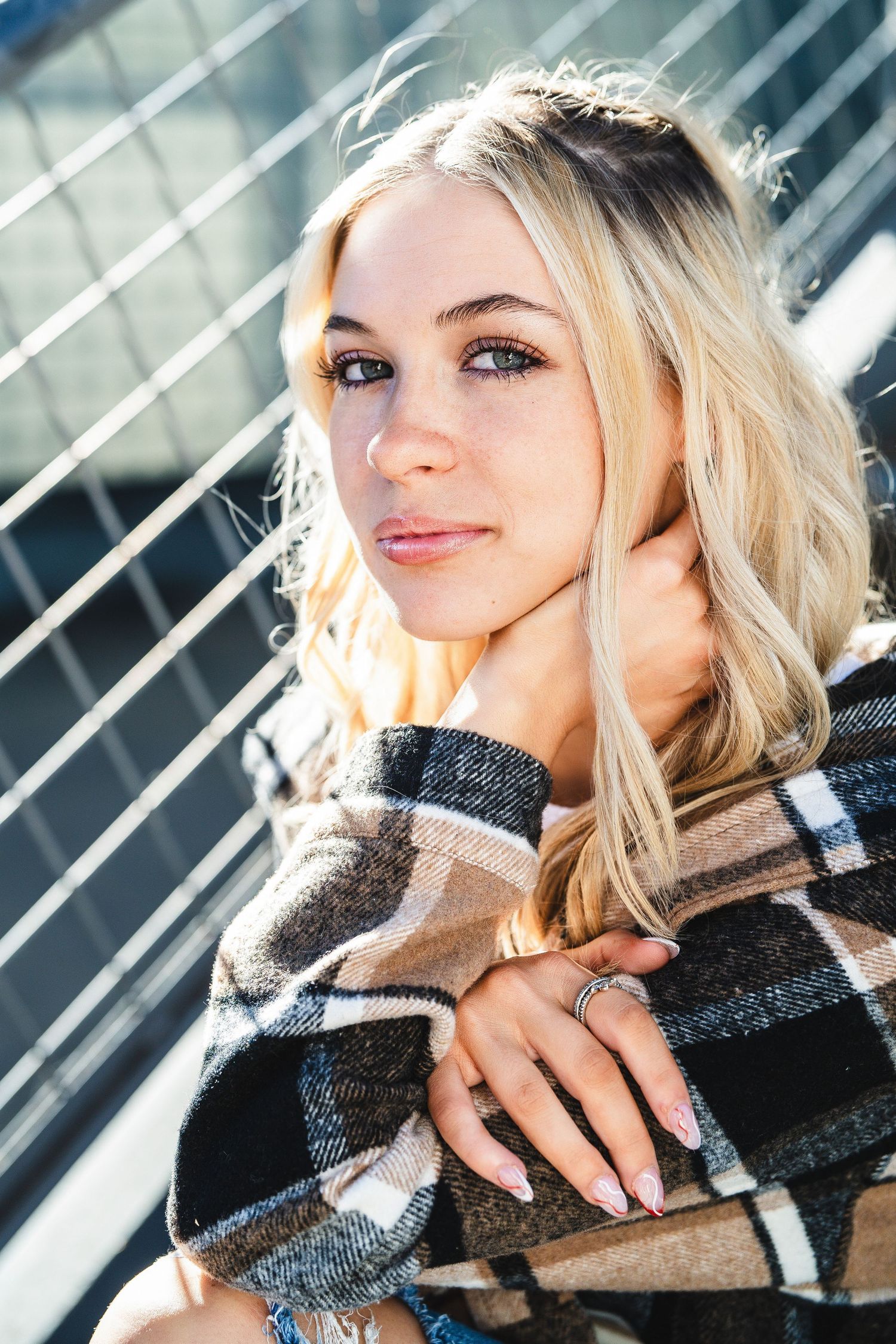 Portrait in warm sunlight showing blonde hair and plaid scarf against diagonal lines background.