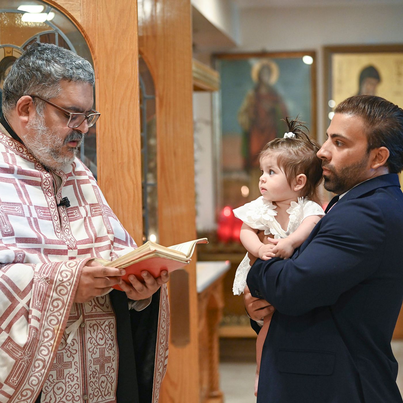 Religious ceremony taking place with priest reading from book.