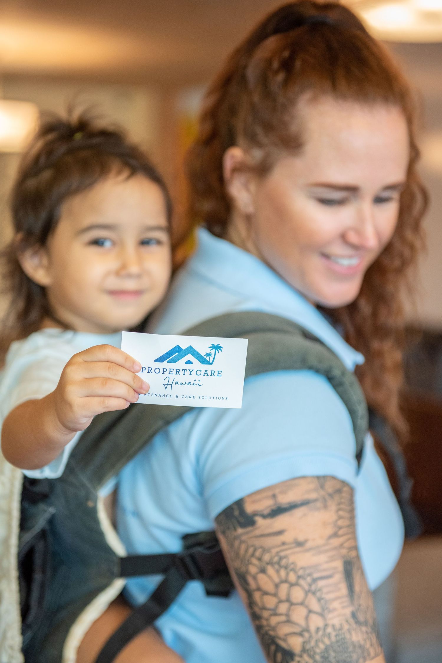 Child holds business card while being carried in baby carrier.