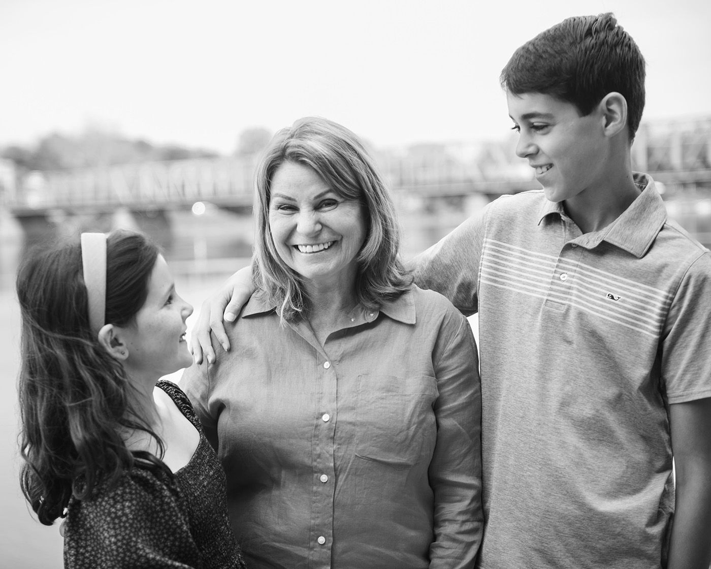 Black and white outdoor portrait of three family members sharing a candid moment together.