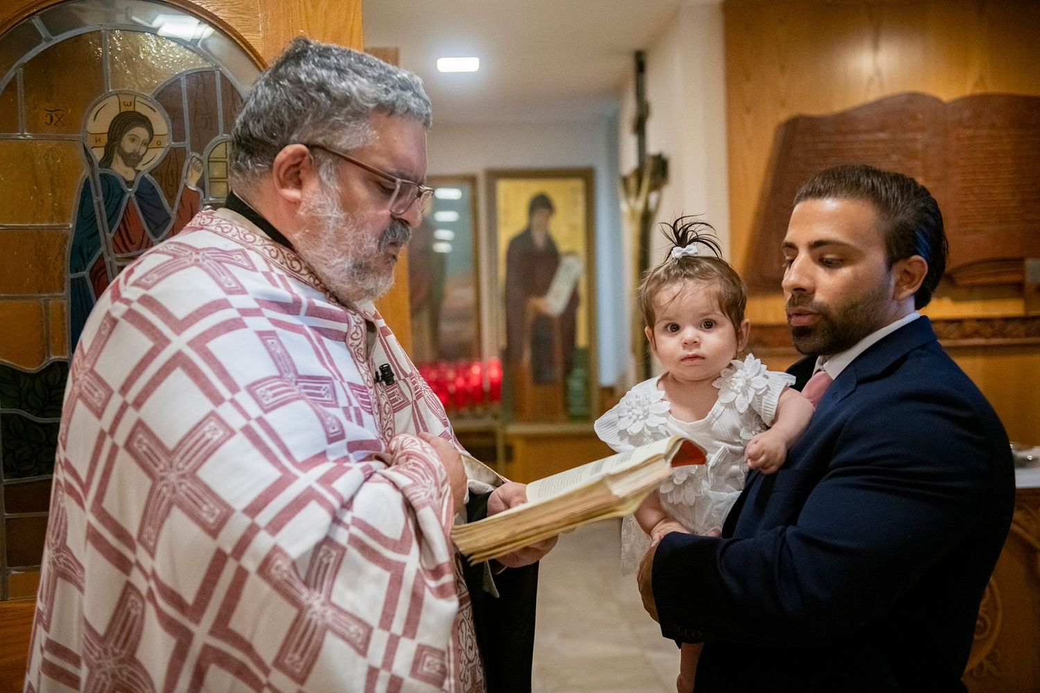 Religious ceremony taking place in church with ornate icons visible in background.