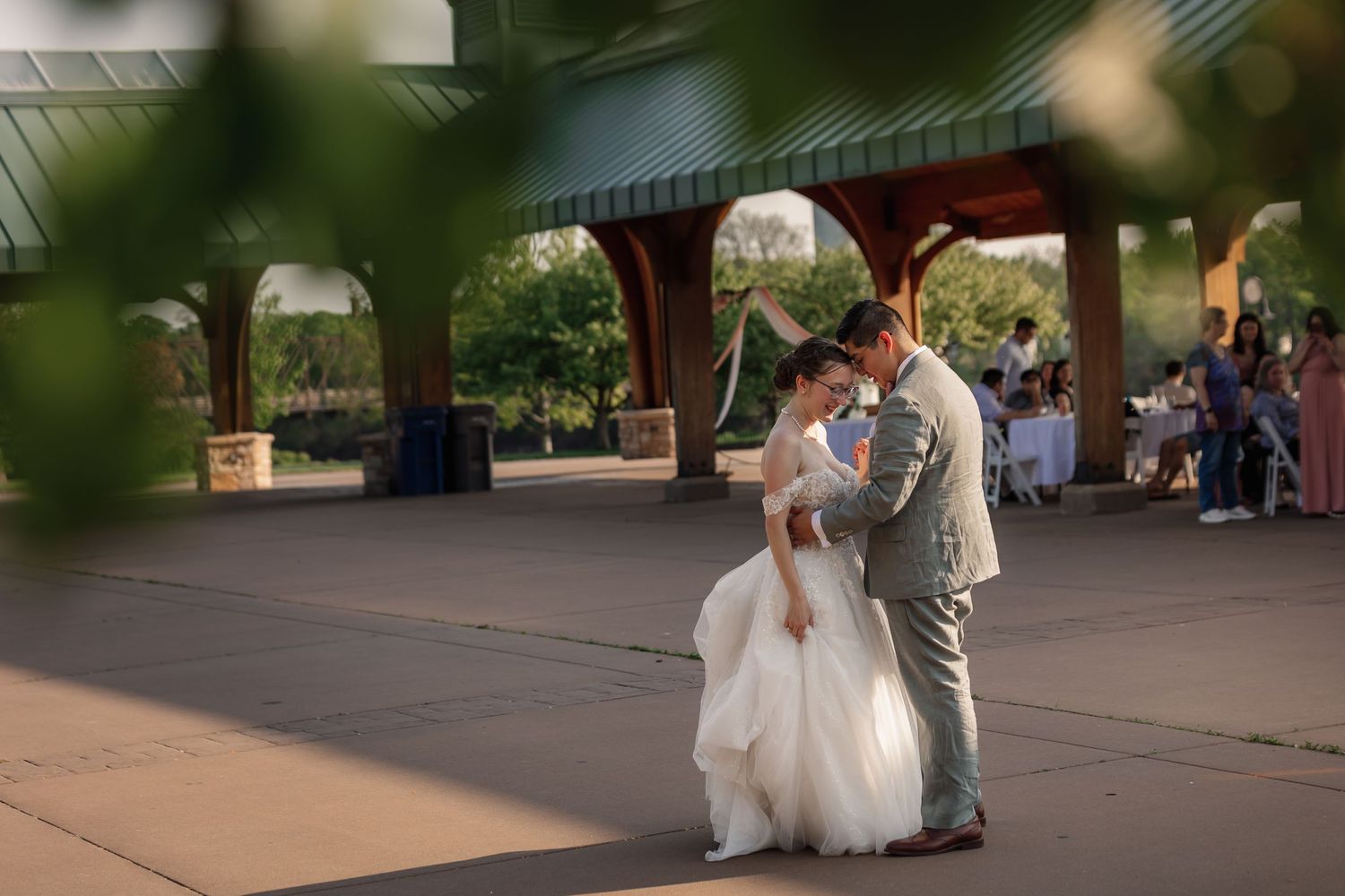 Newlyweds share their first dance under an outdoor pavilion.