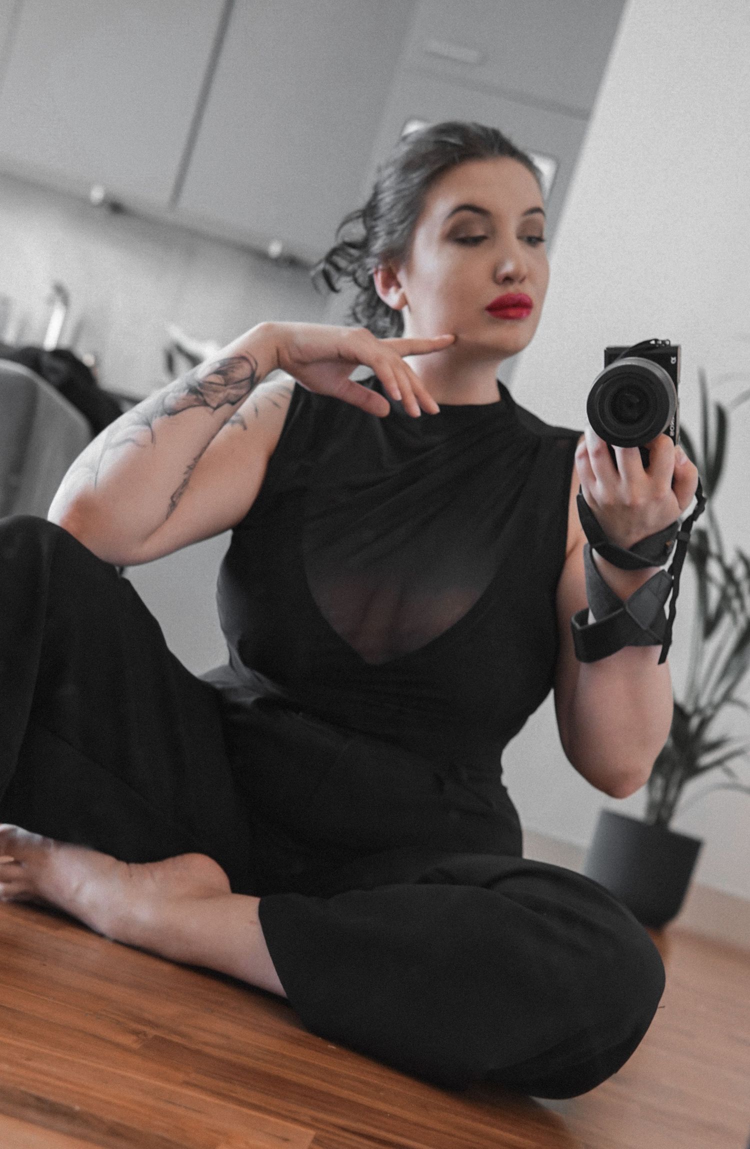 Woman in black clothes, red lips holding a camera and making mirror selfie Boudoir photographer UK Liverpool