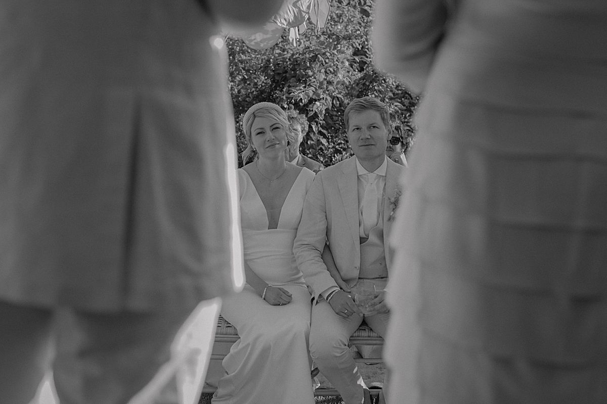 Bride exchanging vows with groom under floral arch at outdoor wedding ceremony