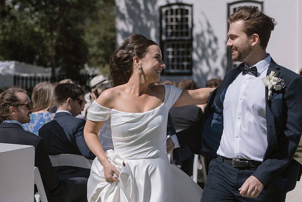Bride and groom sharing a joyful moment at Weltevreden Estate, with elegant floral arrangements and Cape Dutch architecture.