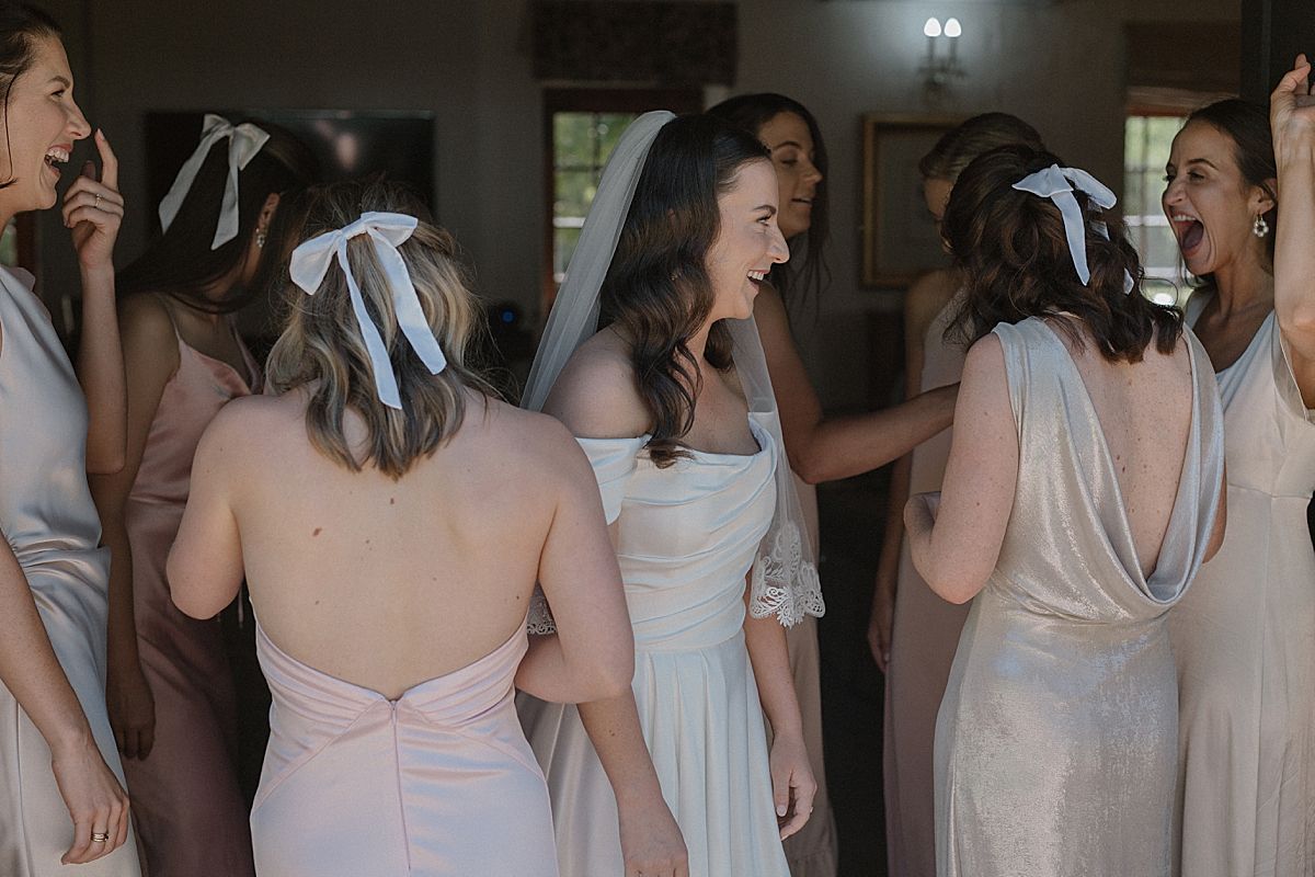Candid moment of bride and bridesmaids helping with dress and veil