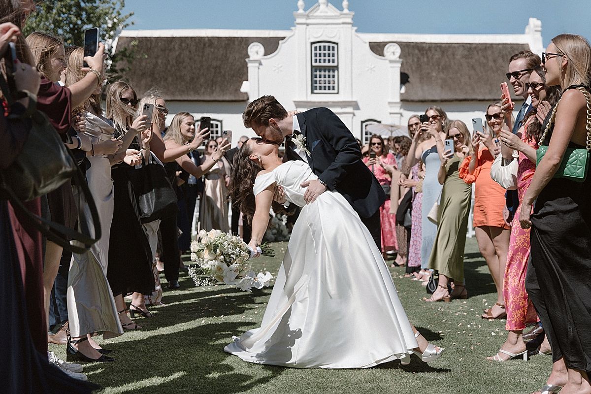 Bride and groom sharing a joyful moment at Weltevreden Estate, with elegant floral arrangements and Cape Dutch architecture.