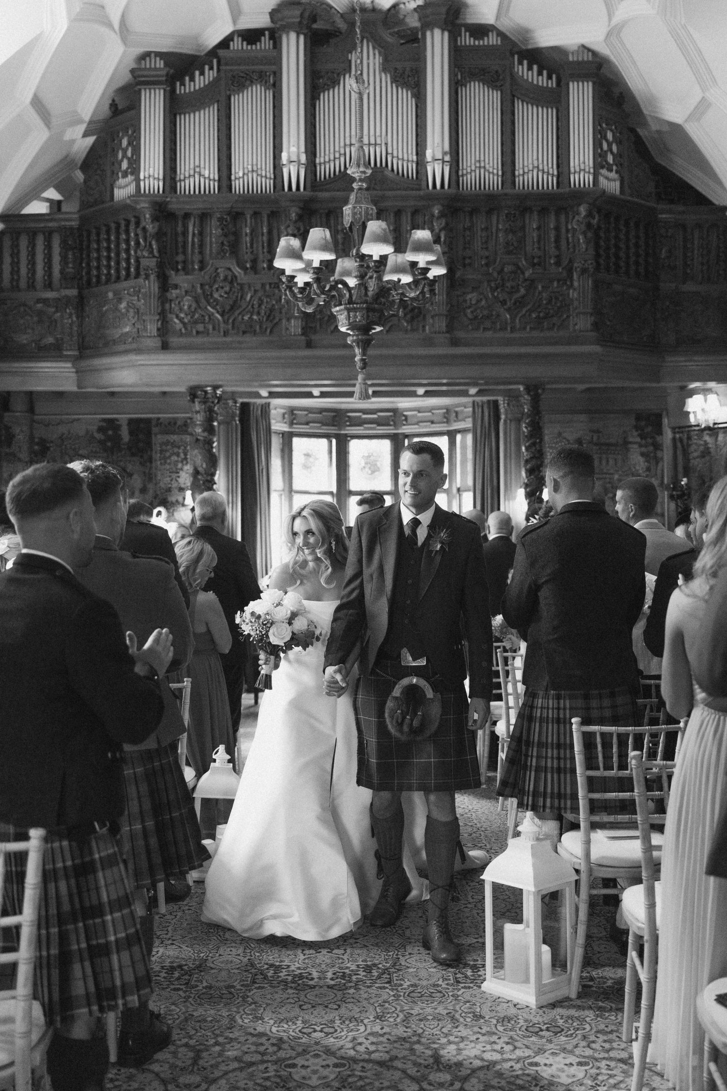 Black and white panoramic sequence of a wedding ceremony inside an ornate church with guests in traditional Scottish kilts.