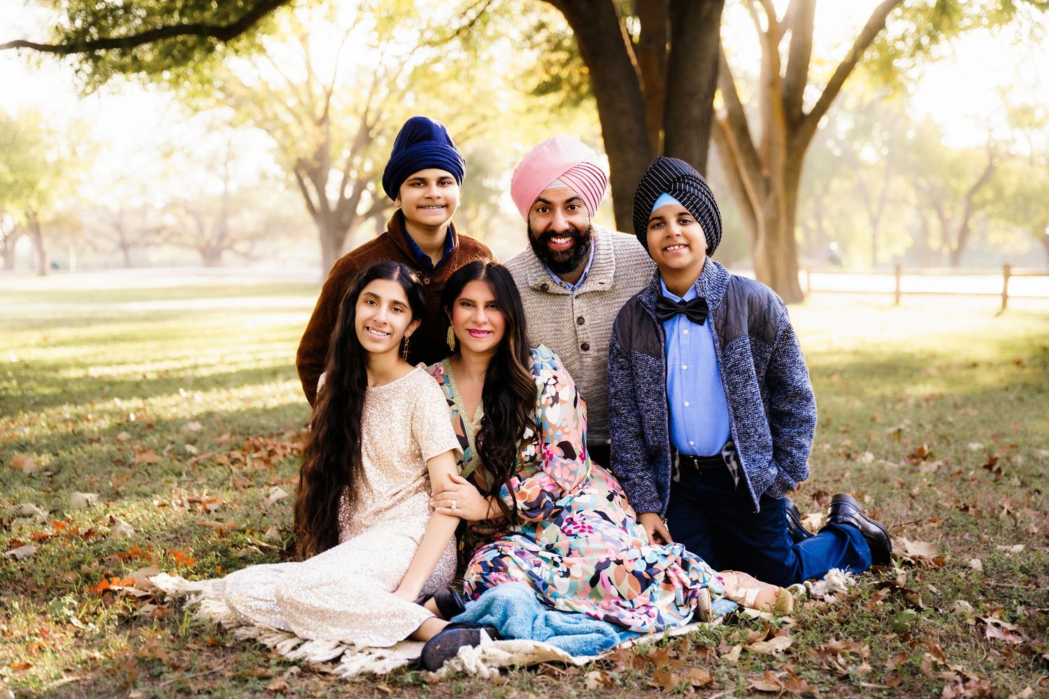 A group enjoying a warm autumn day outdoors with fallen leaves scattered around them in a park setting.