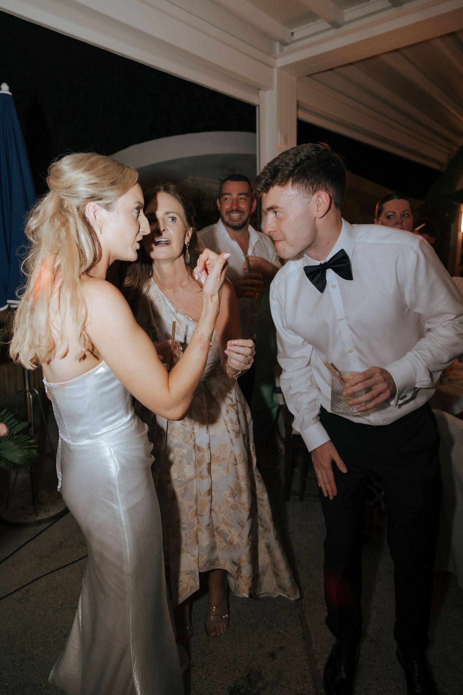 Wedding guests dancing and socializing at an evening reception in formal attire.
