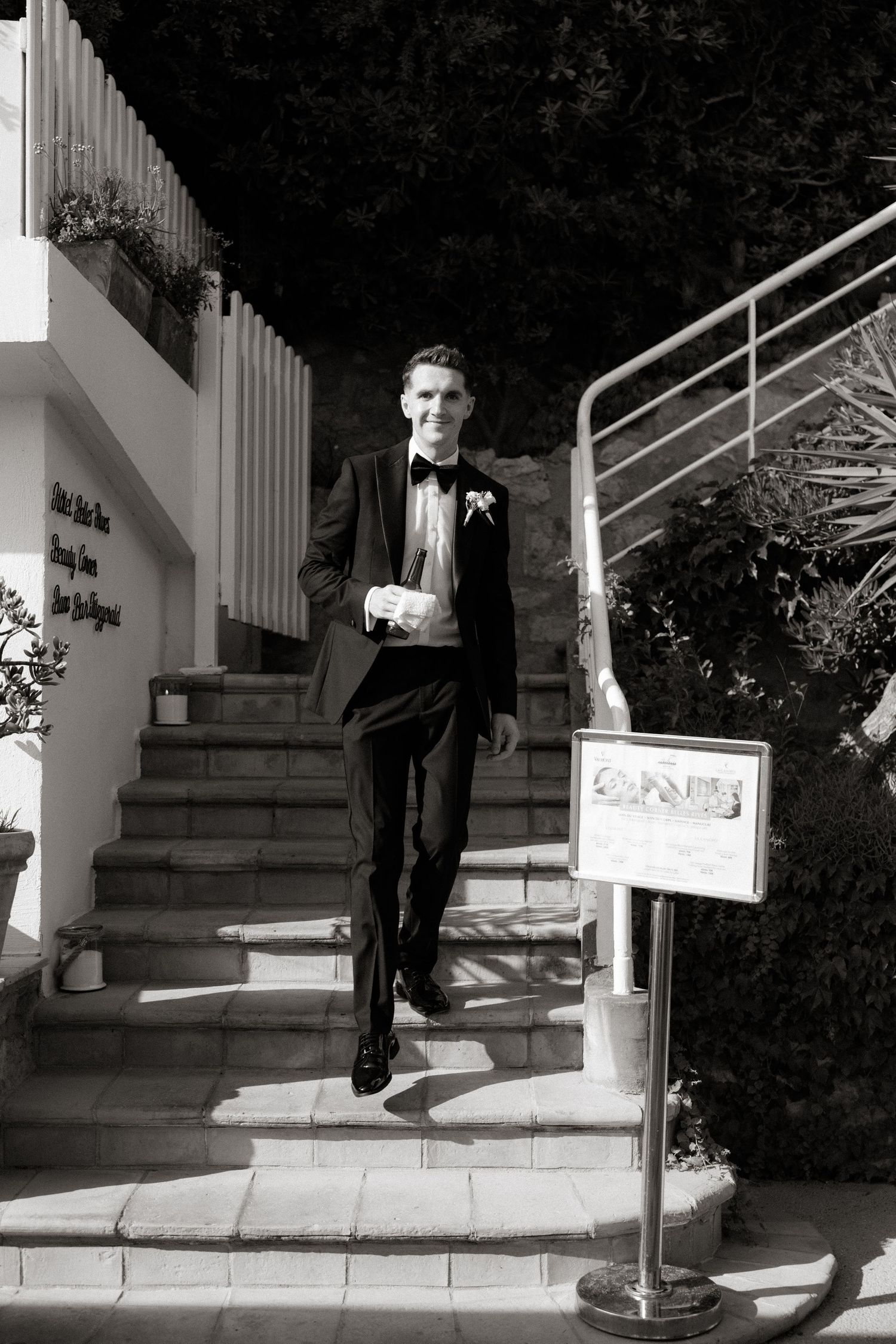 Black and white photo showing a person walking down stone steps in formal attire.