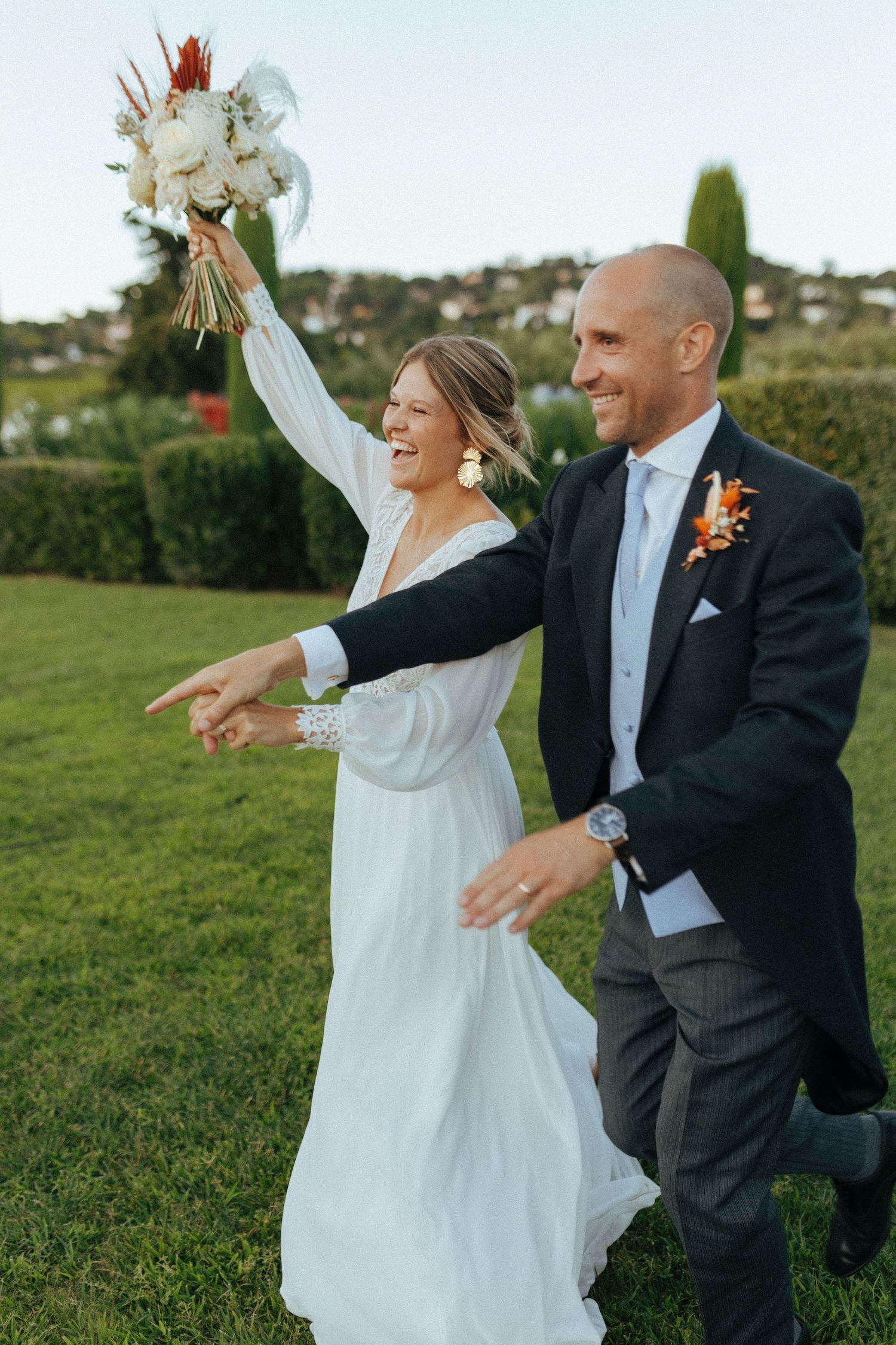 Joyful celebration on grassy hillside with raised bouquet and matching poses.