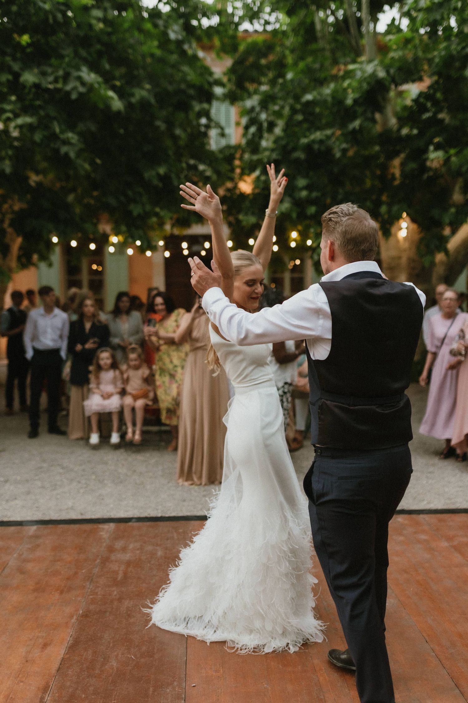 First dance moment on outdoor dance floor with string lights and evening ambiance.