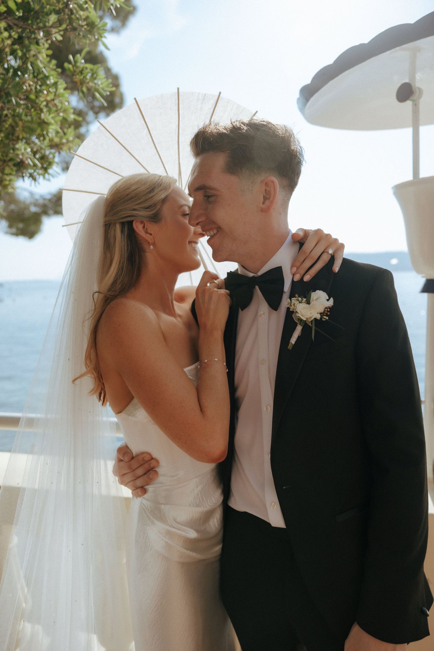 A romantic wedding couple shares intimate moments by the ocean with sheer white curtains billowing in the breeze.