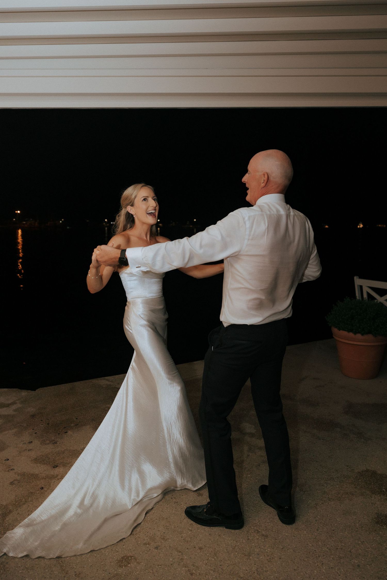A couple dances together at their wedding reception with a nighttime backdrop.