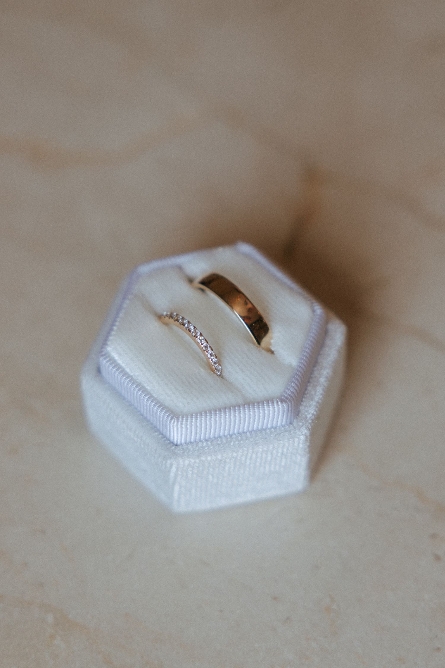 A delicate gold engagement ring nestled in a white hexagonal ring box shown from multiple angles.