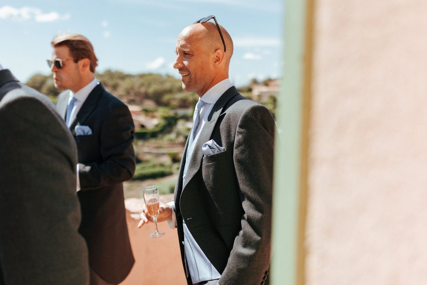Formal-dressed guests at an outdoor wedding venue with desert landscape in background.