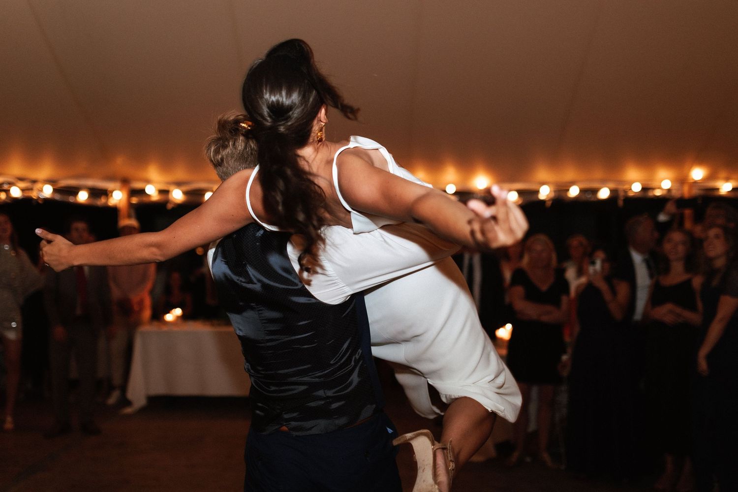 Dramatic dip during a wedding dance under warm tent lighting.