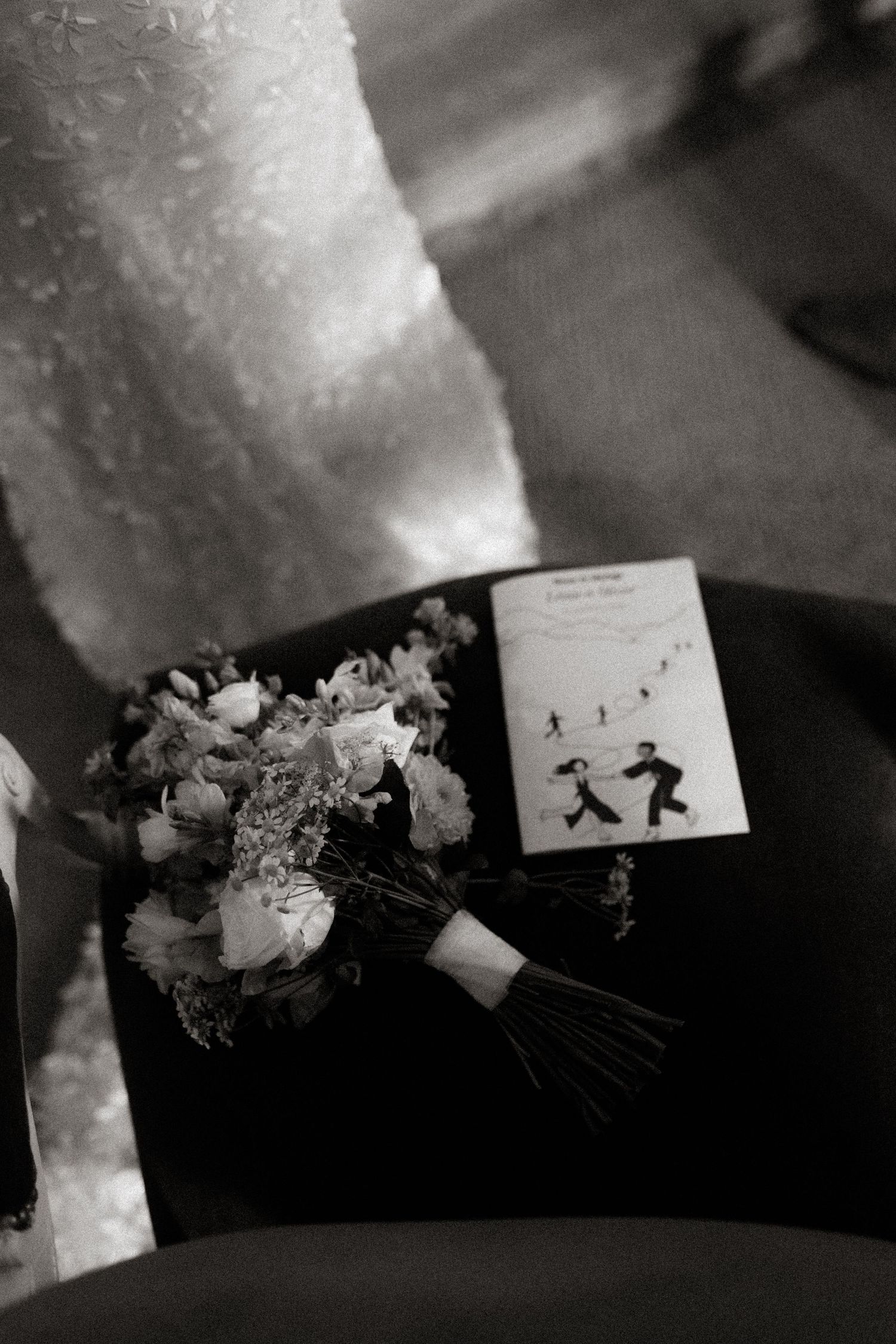 Black and white photo of a wedding bouquet next to a small card showing silhouettes dancing.