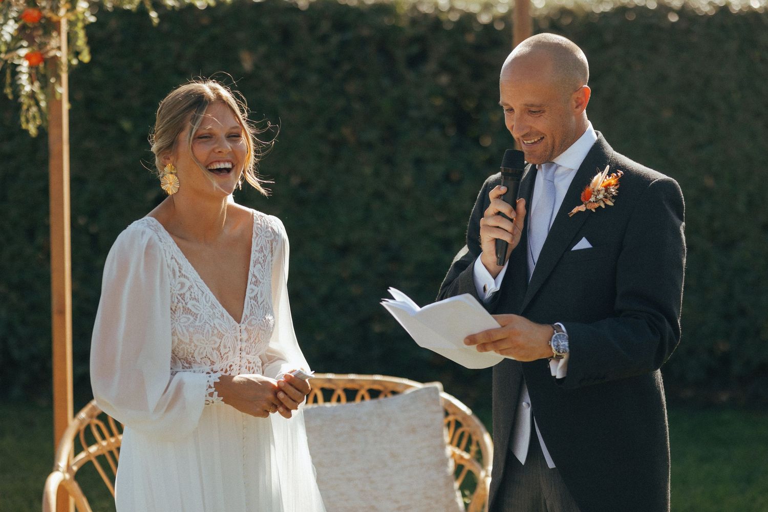 A joyful wedding ceremony moment captured outdoors with the couple sharing laughter during the vow exchange.