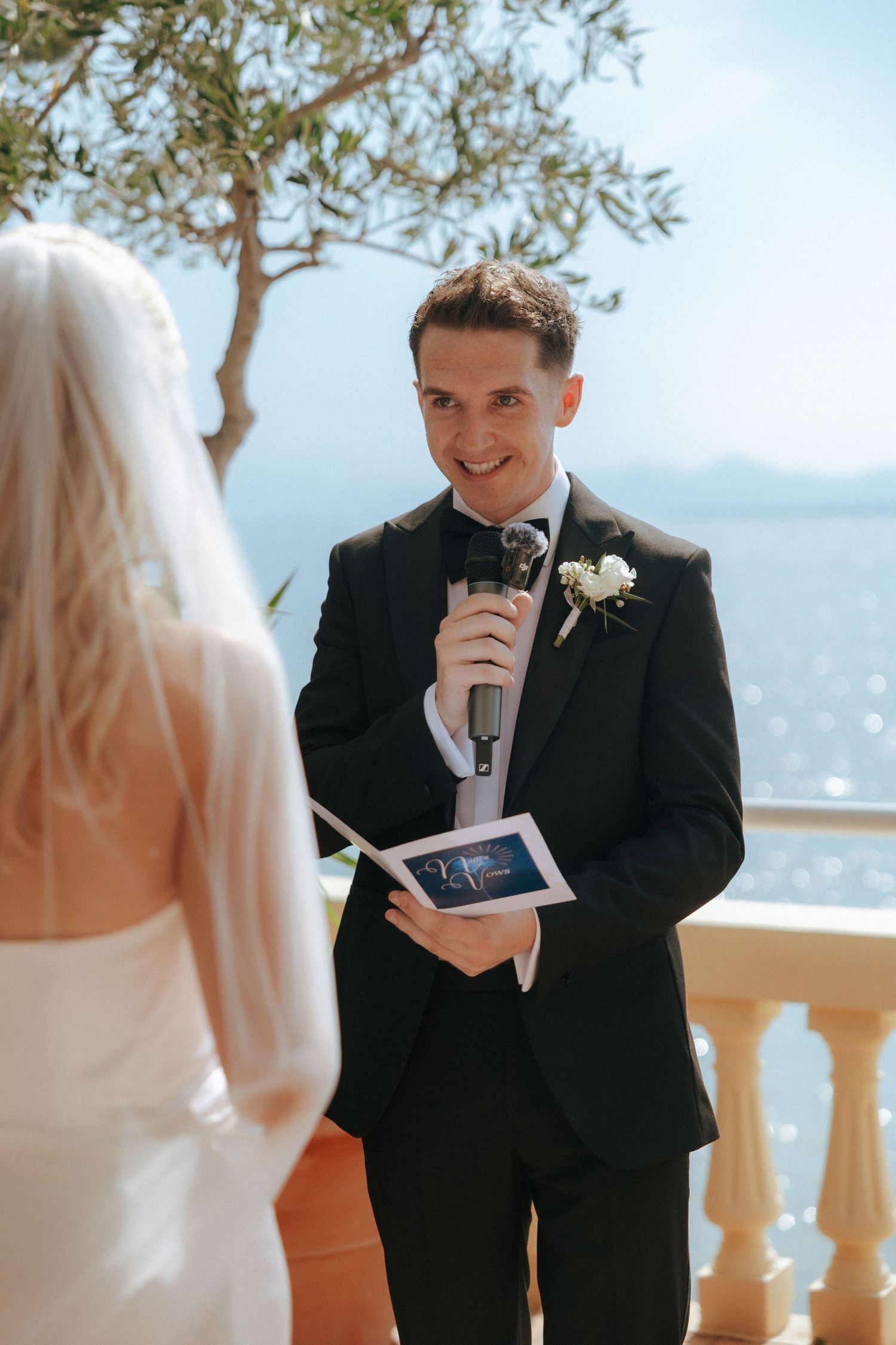 An outdoor wedding ceremony with a beautiful coastal view in the background.