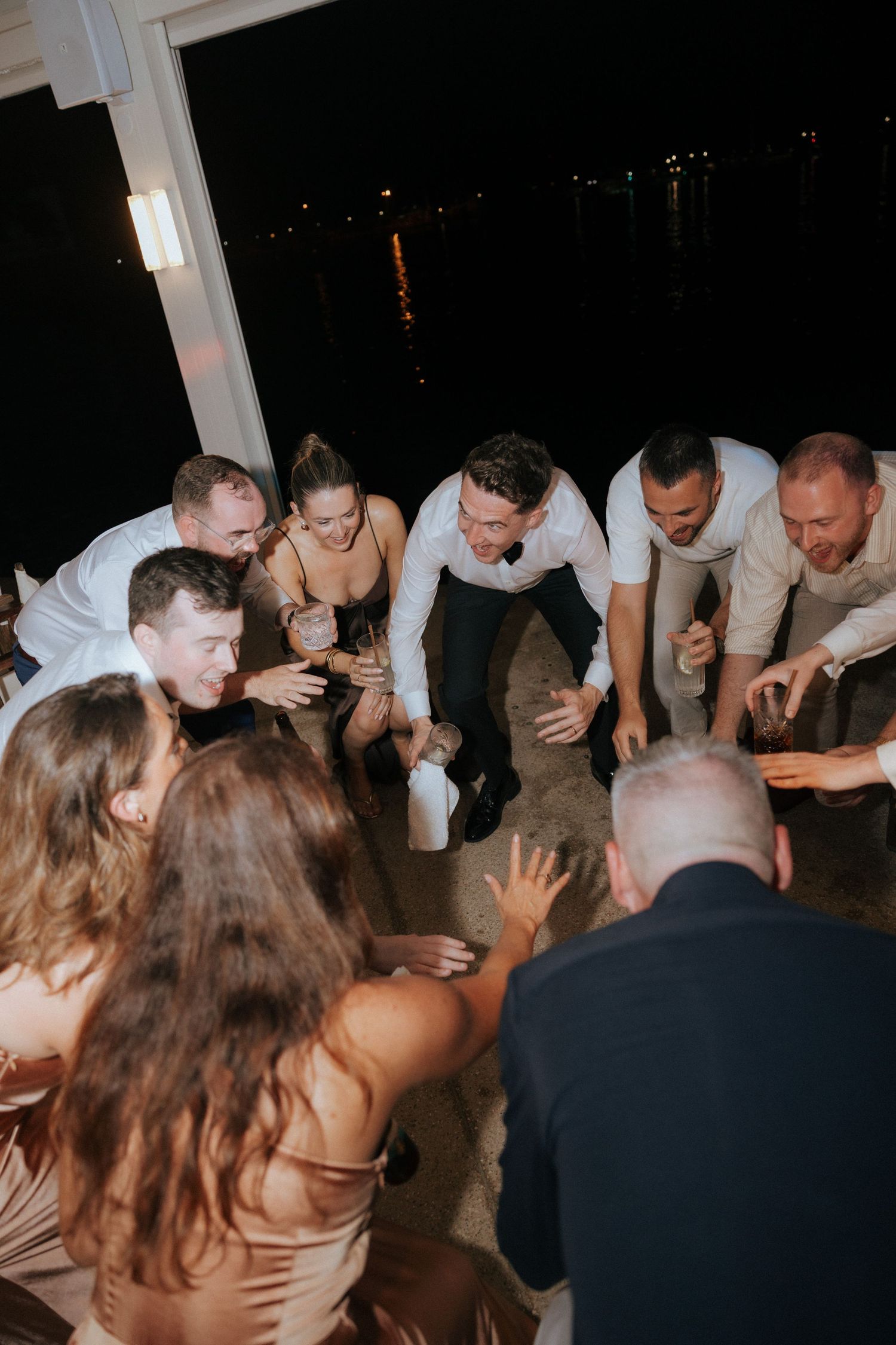 Group of wedding guests gather closely on the dance floor during an evening celebration.