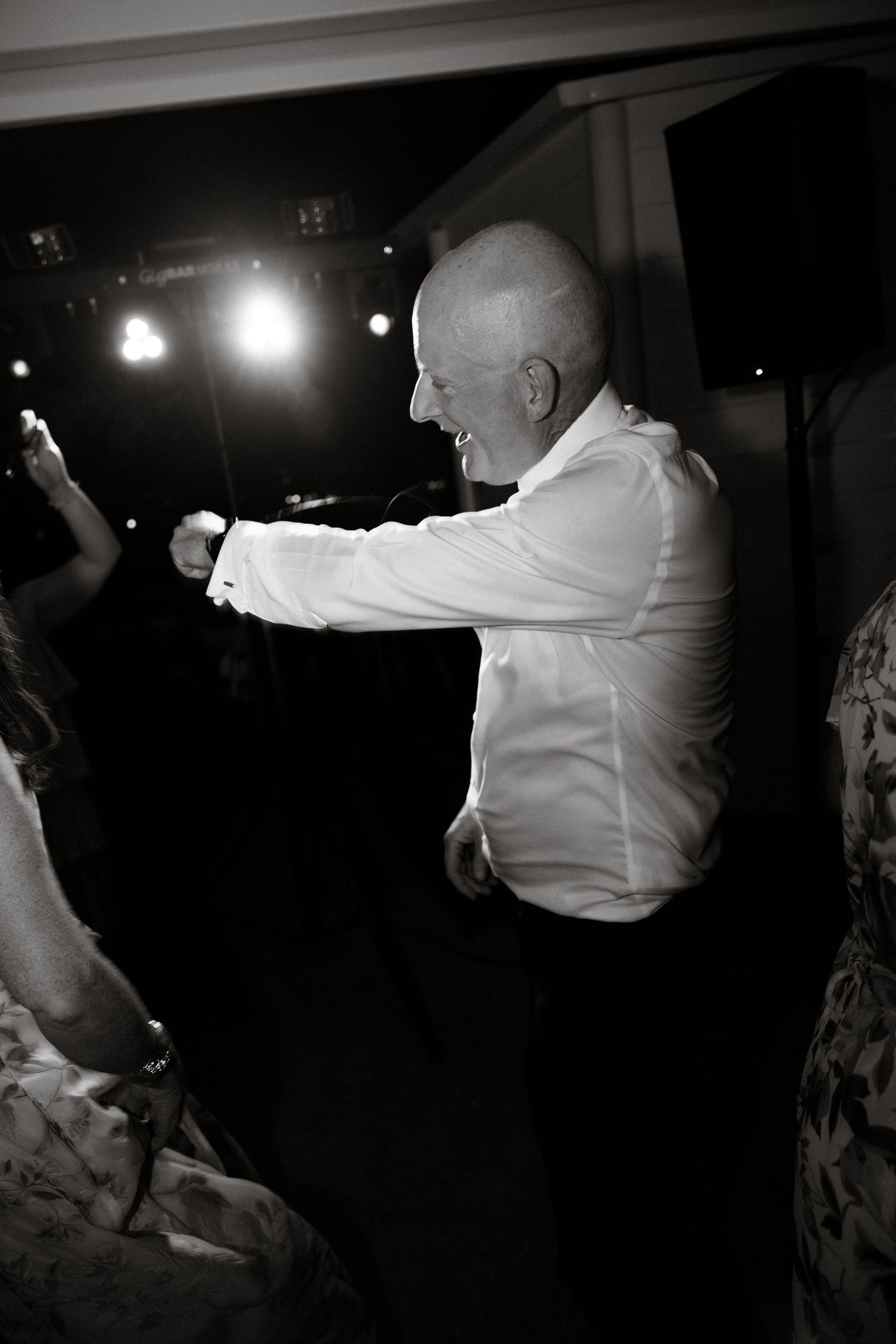 Wedding guests dance with sparklers creating light trails in the dark.