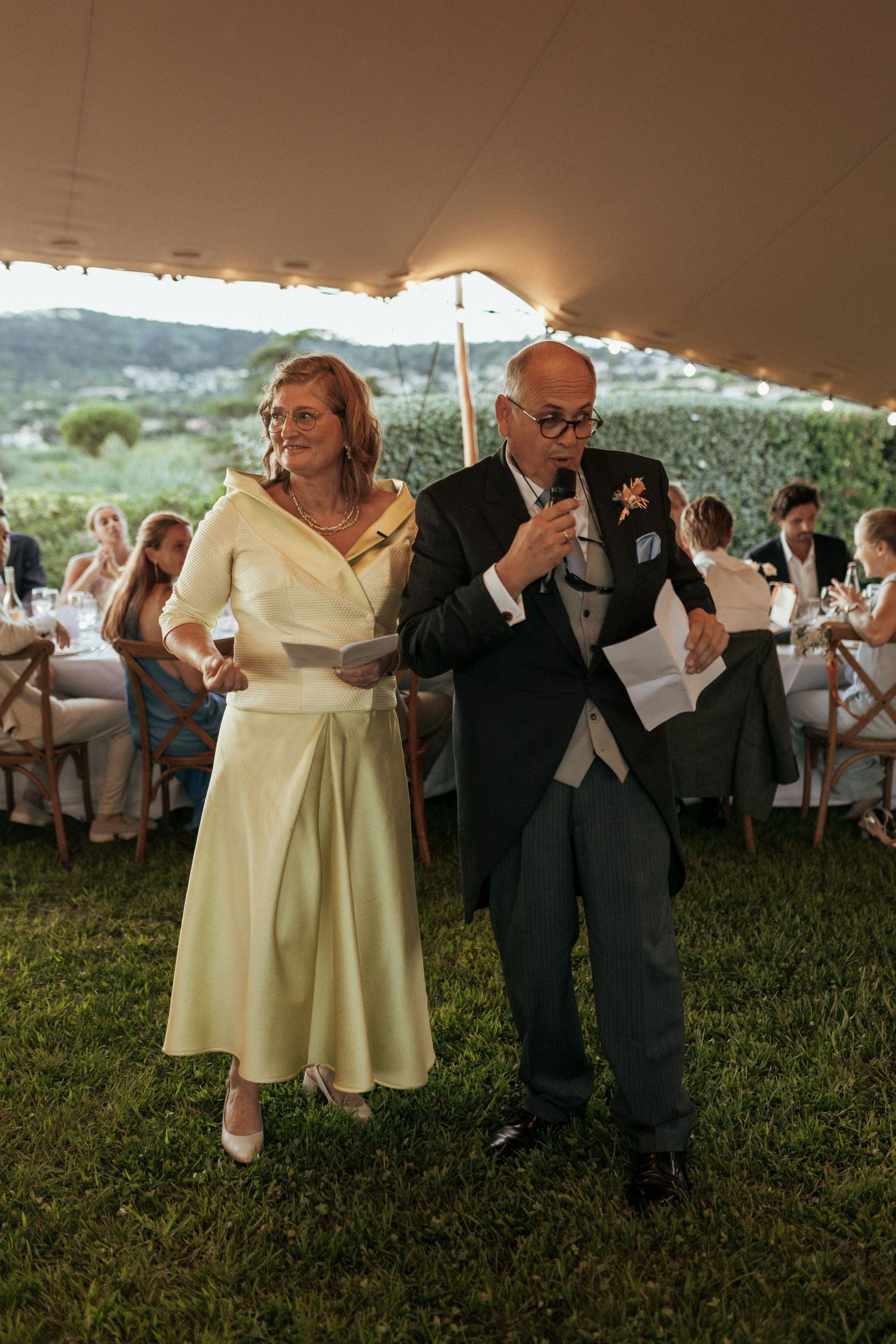 Guests dance and celebrate under a tent during an outdoor wedding reception.