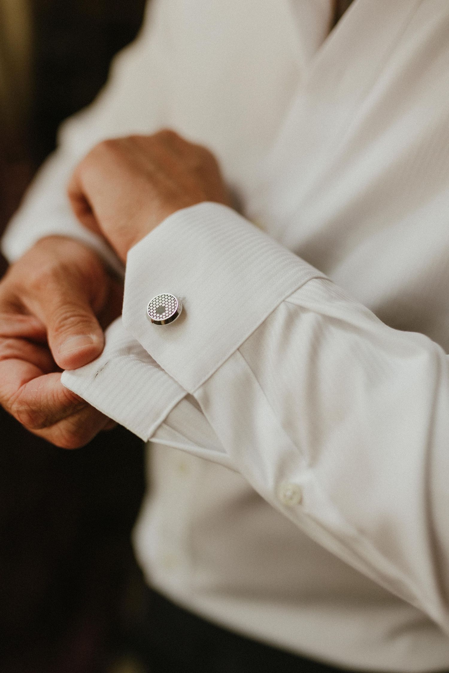 Detail shot of white dress shirt sleeve with decorative silver cufflink.