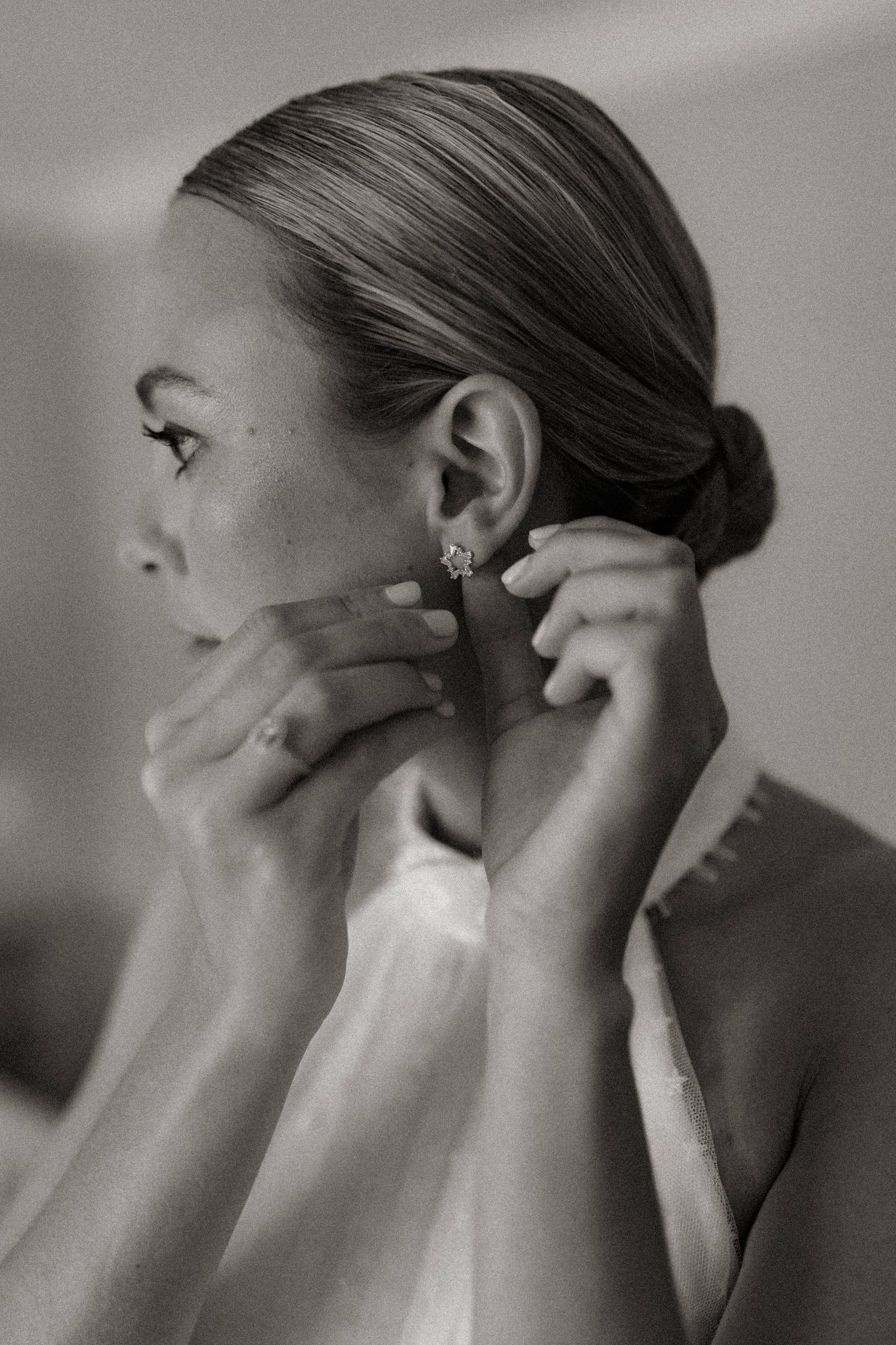 Close-up black and white portrait showing delicate earring detail during bridal preparation.