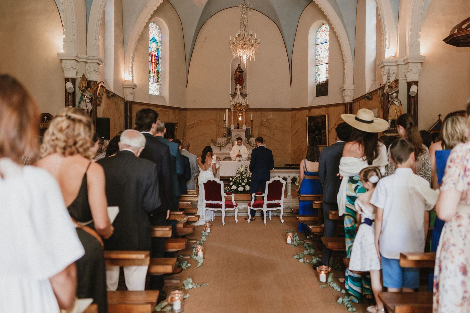 Inside a traditional church with arched ceilings, wedding guests gather for a ceremony in the pews.