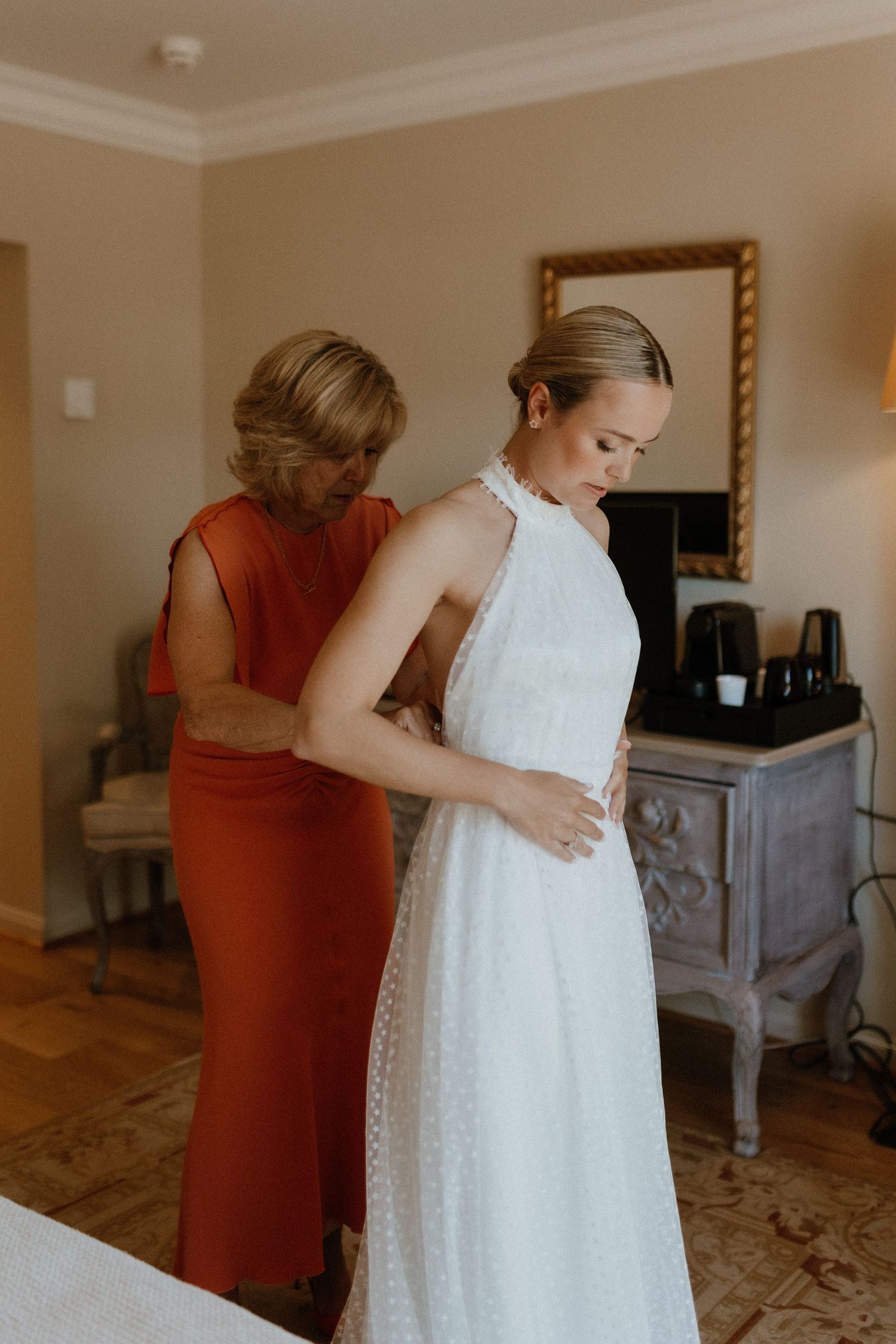 Final wedding dress fitting moment in a sunlit room with elegant white gown.