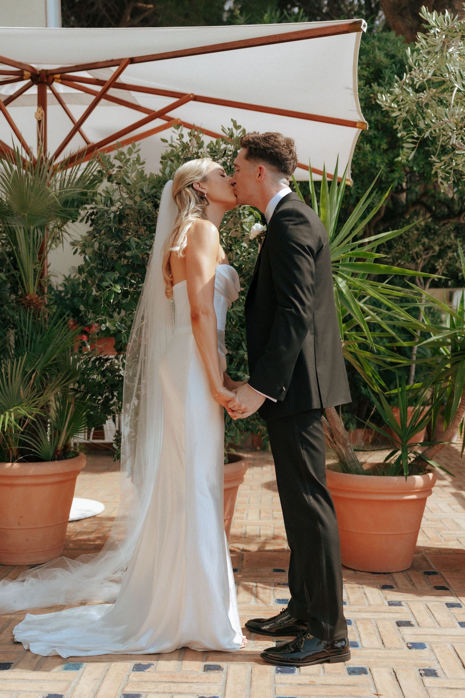 First look moment between couple under wooden pergola surrounded by tropical plants.