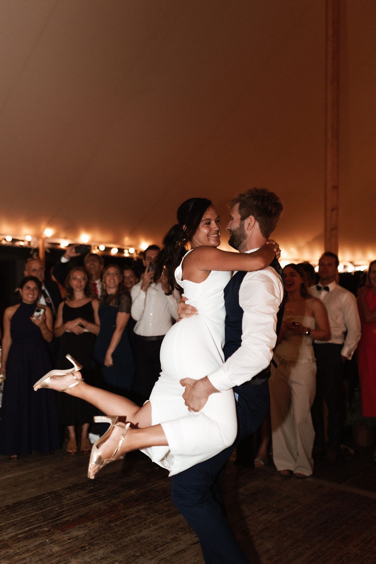 A newlywed couple shares a dramatic dance moment with the bride being dipped on a crowded dance floor.