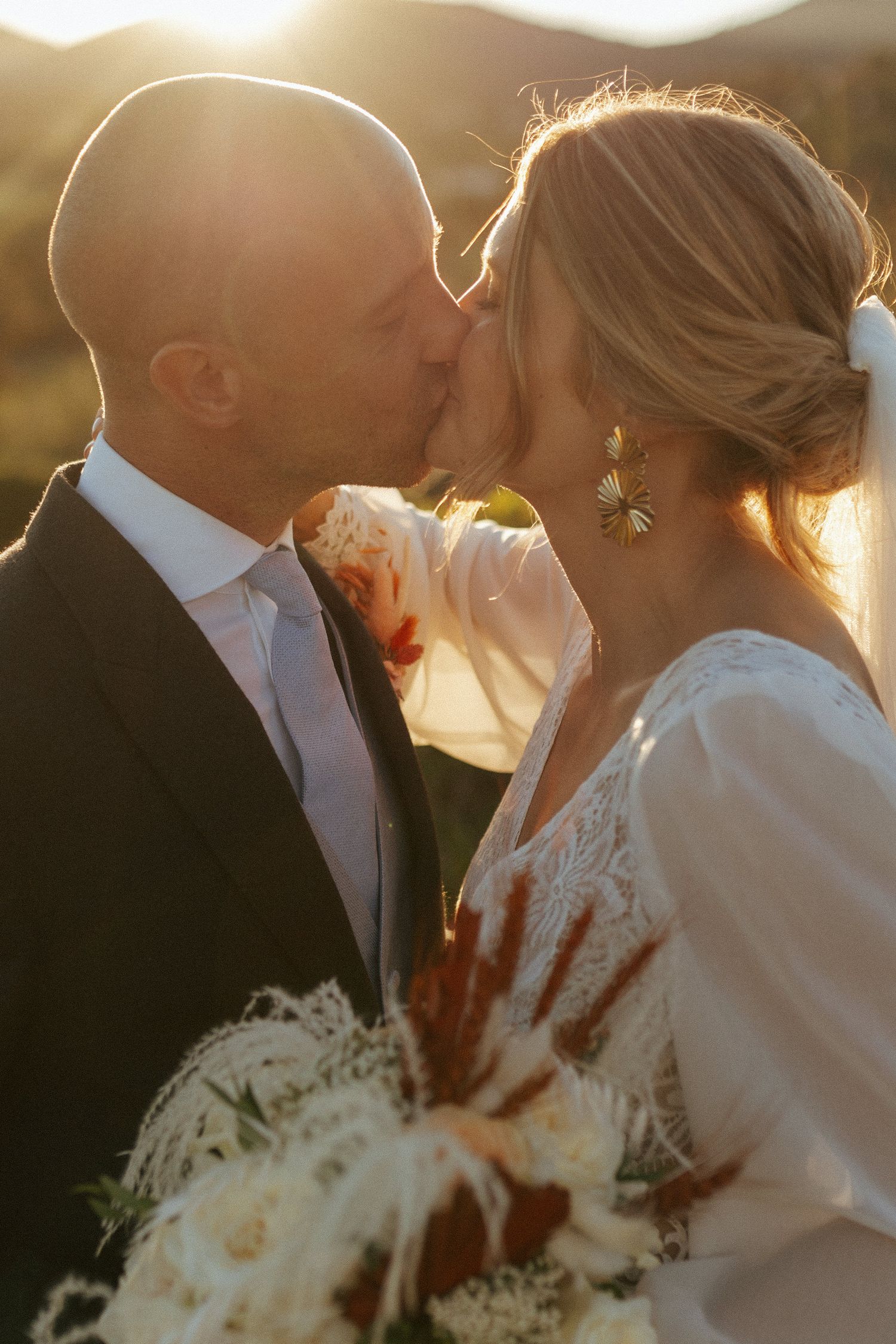 Romantic sunset wedding portrait showing a tender kiss with mountains in the background.