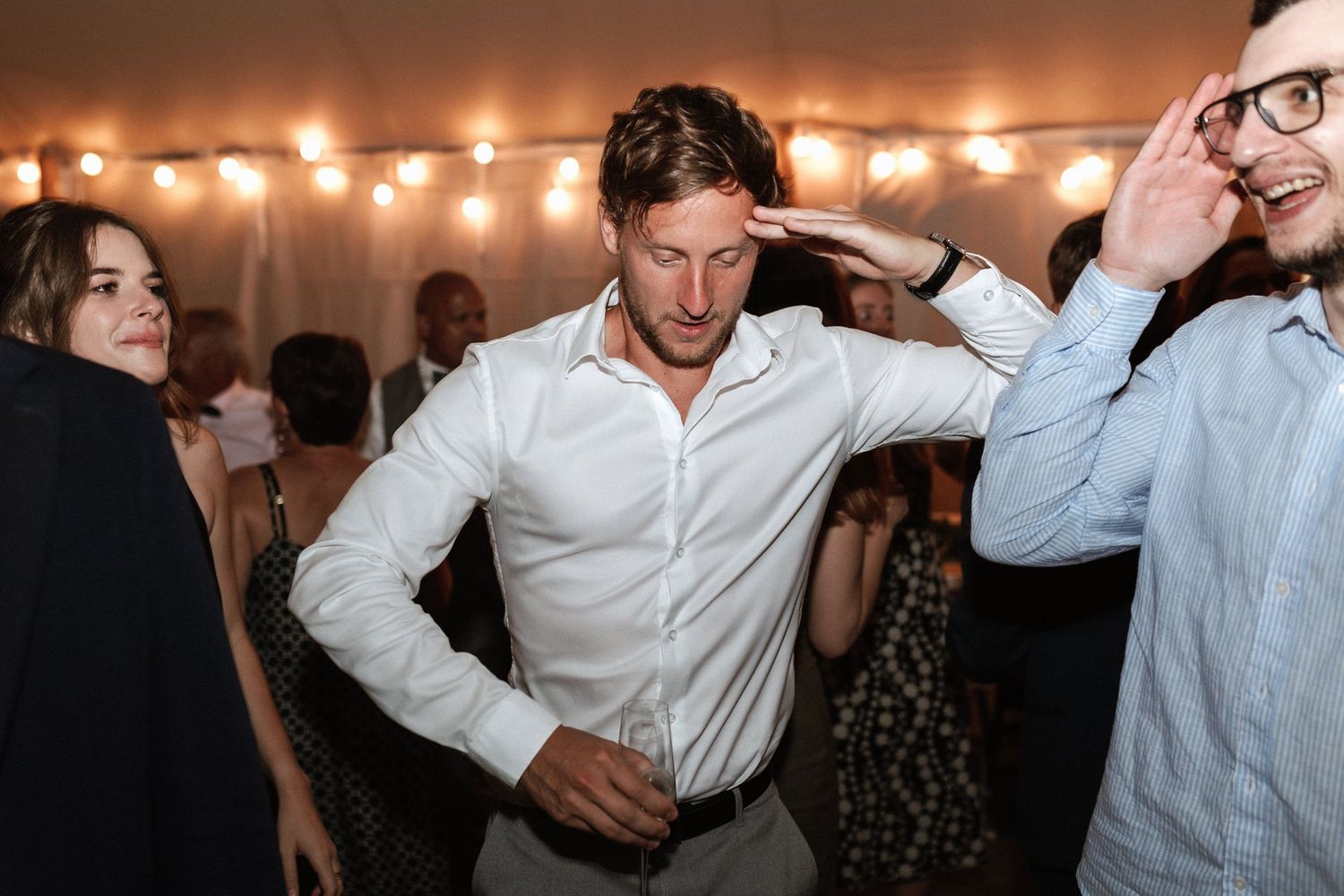Wedding reception dance party with string lights creating warm ambient glow.