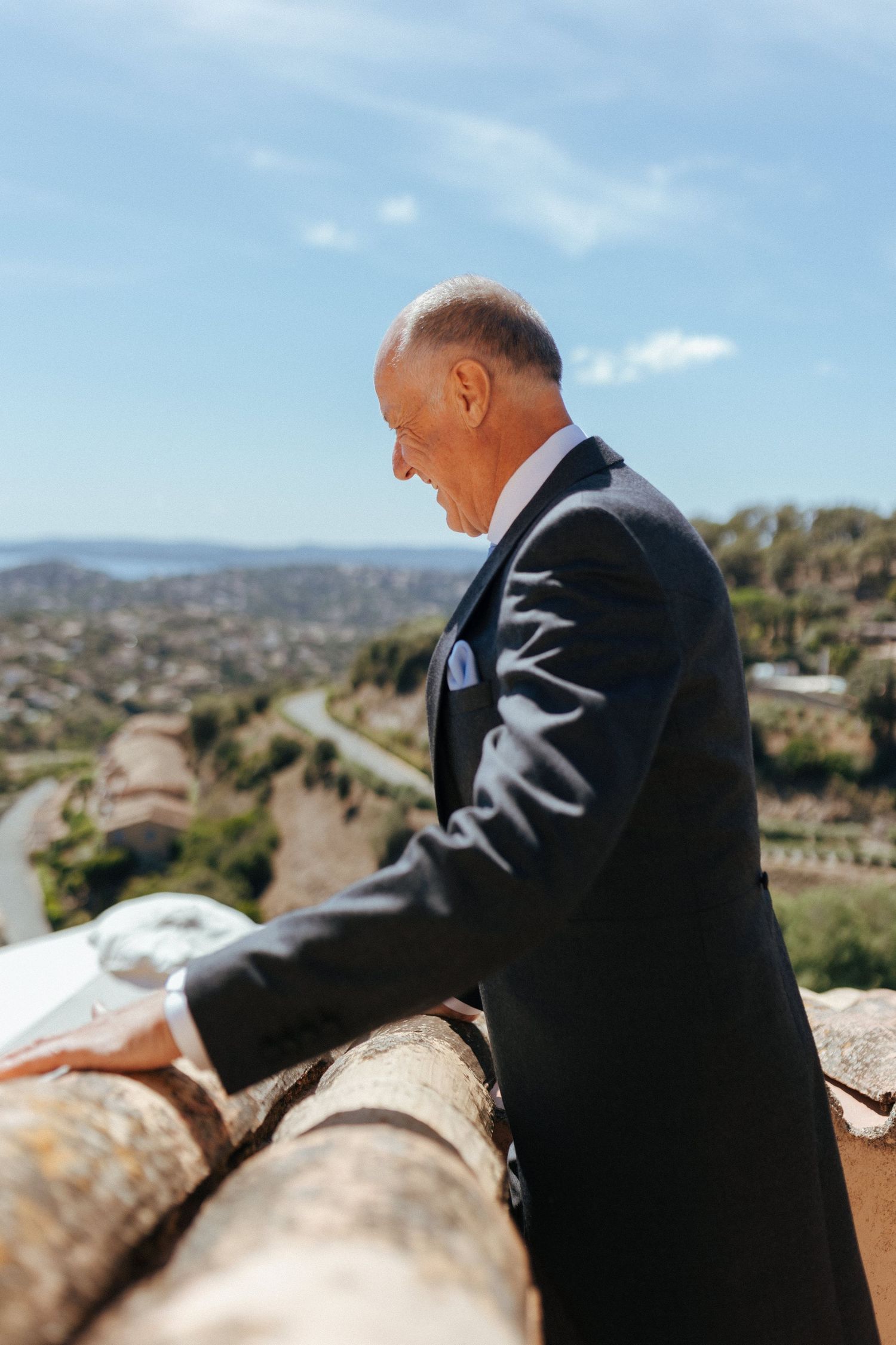 Suited figure overlooking mountainous landscape on sunny day.