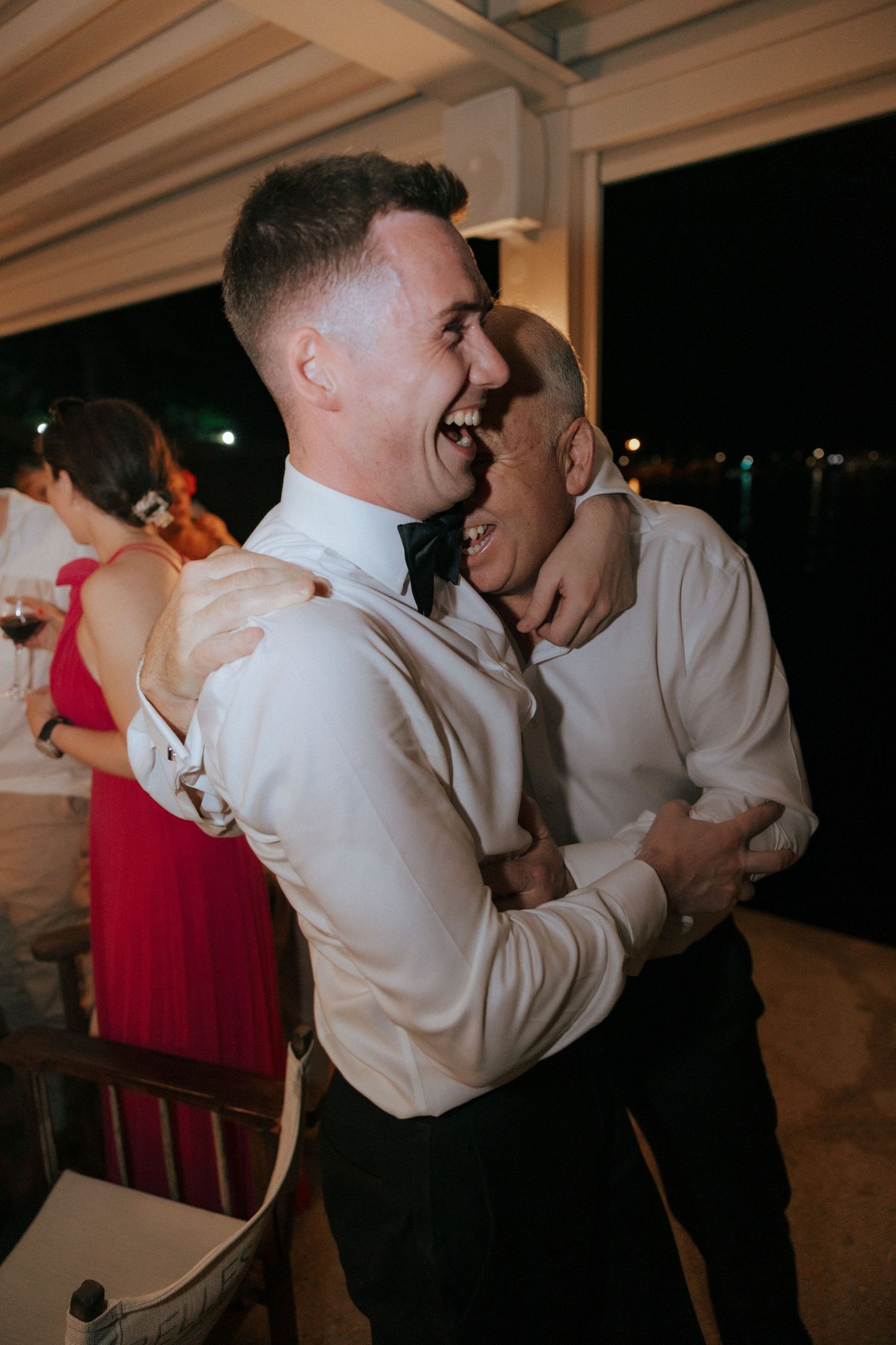 Two people sharing a joyful laughing moment during a wedding reception celebration.