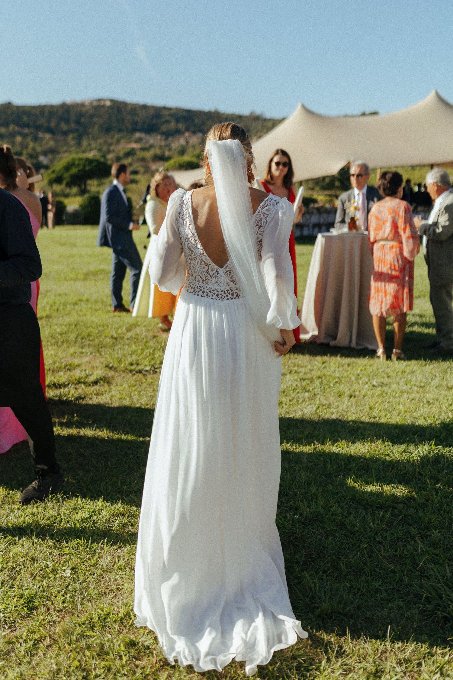 Elegant white wedding dress with lace back detail shown at outdoor reception.