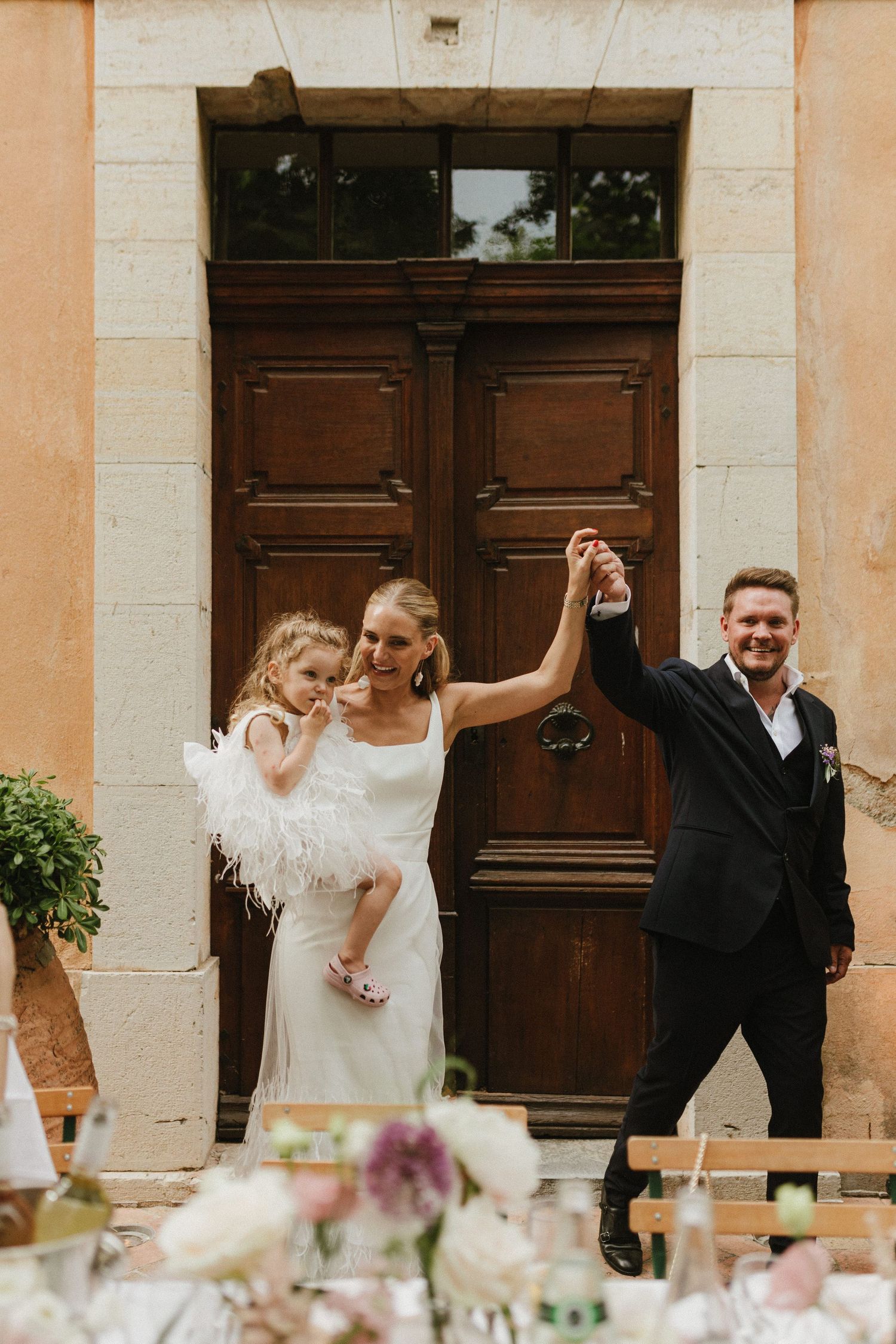 Celebratory moment at a rustic venue entrance with brown wooden doors.