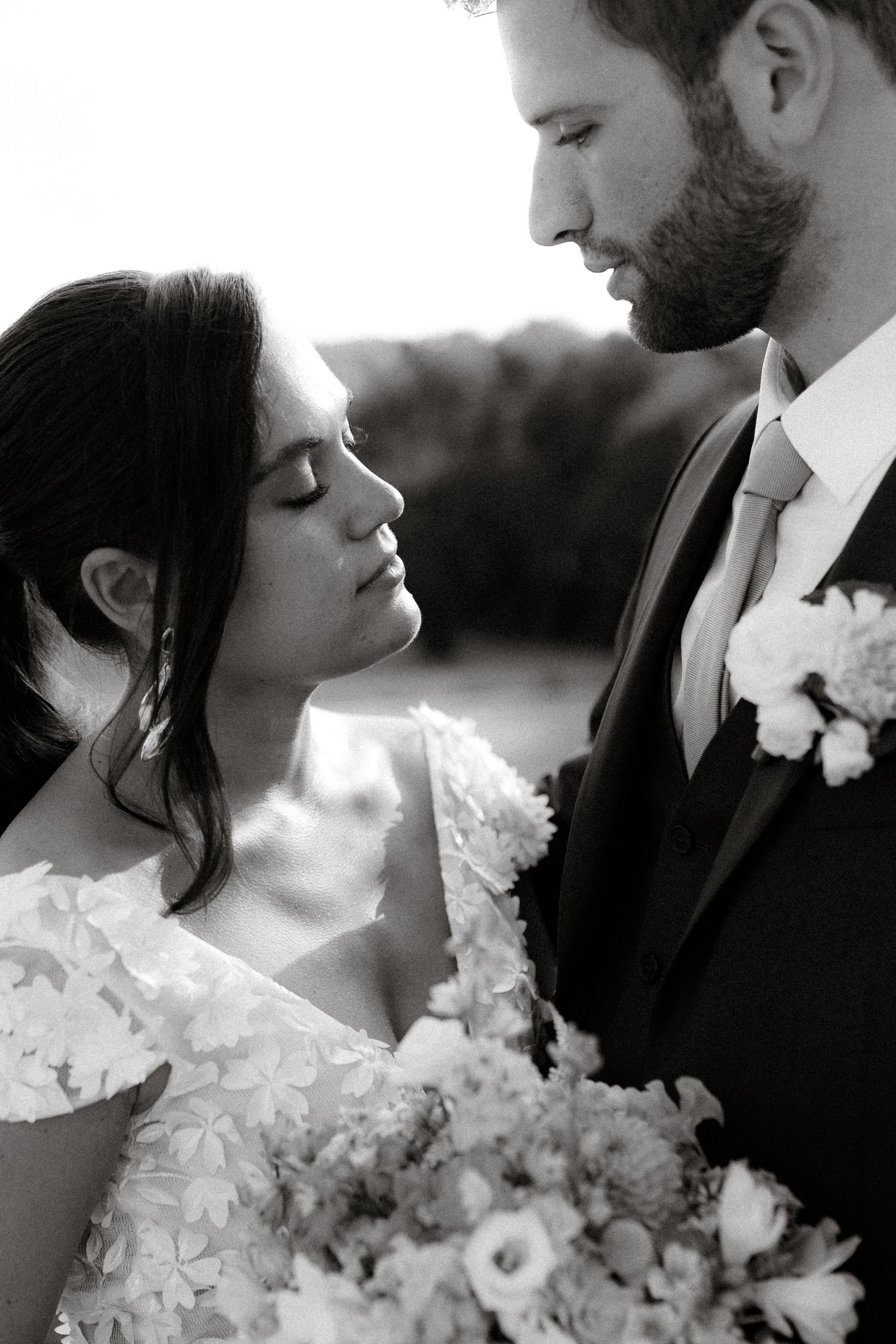 A romantic black and white portrait of a bride and groom with delicate lace and floral details.