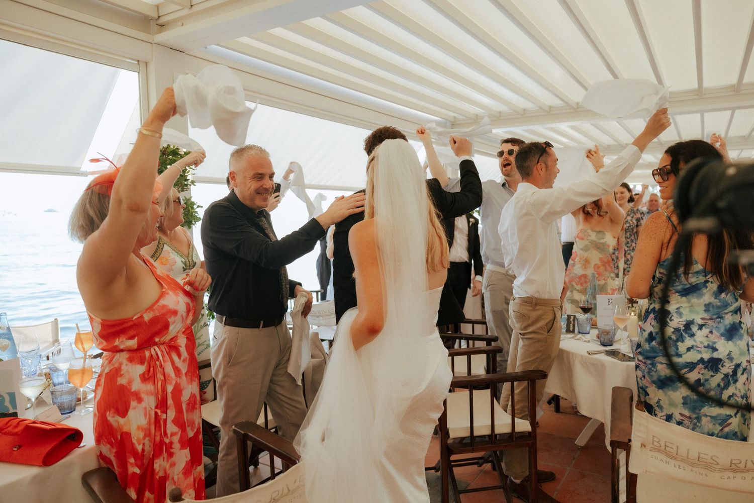 Wedding guests enjoy dancing and celebrating on an outdoor covered patio during a reception celebration.