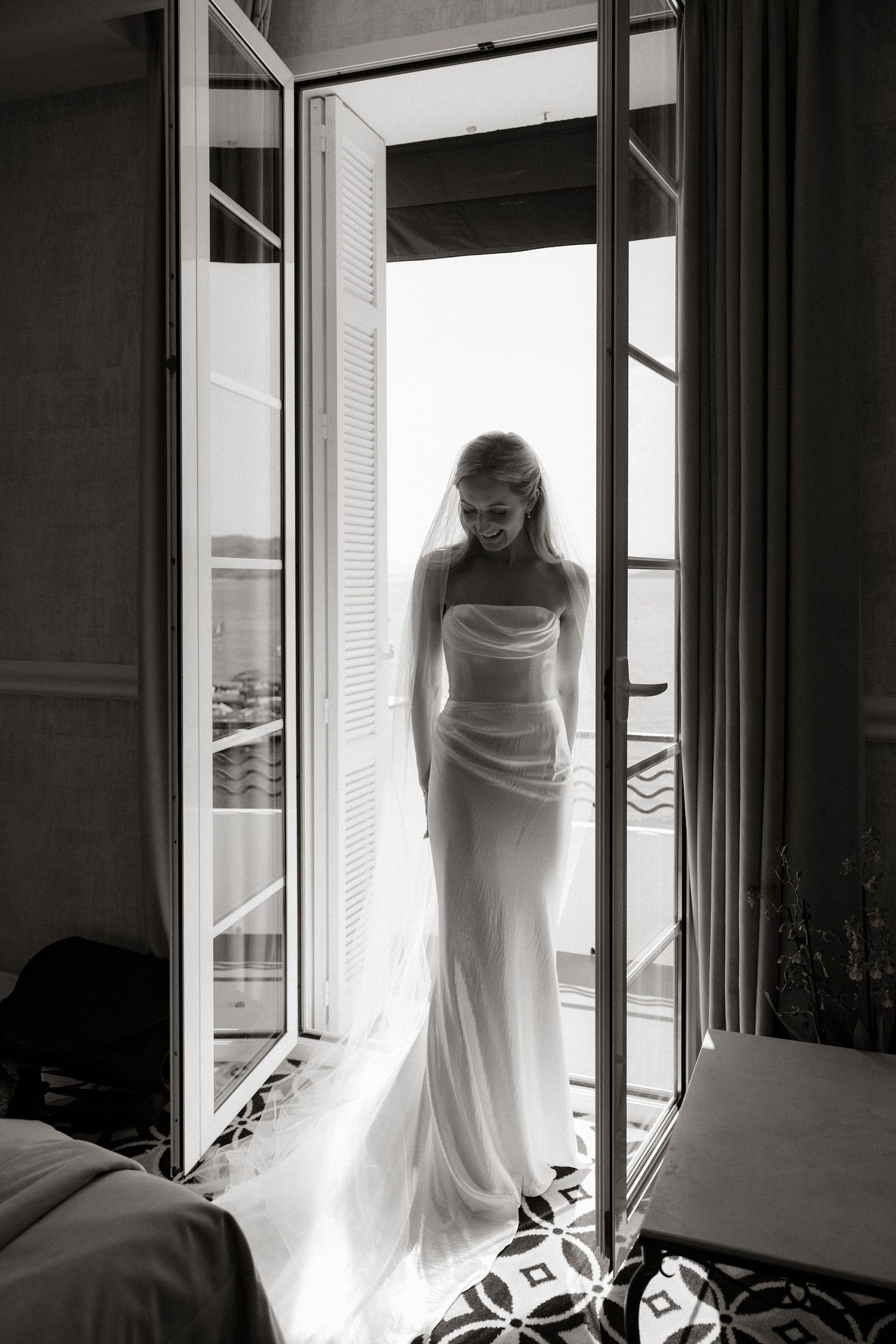 A silhouette of a person in a flowing white wedding dress stands elegantly in a bright doorway creating a dramatic effect.