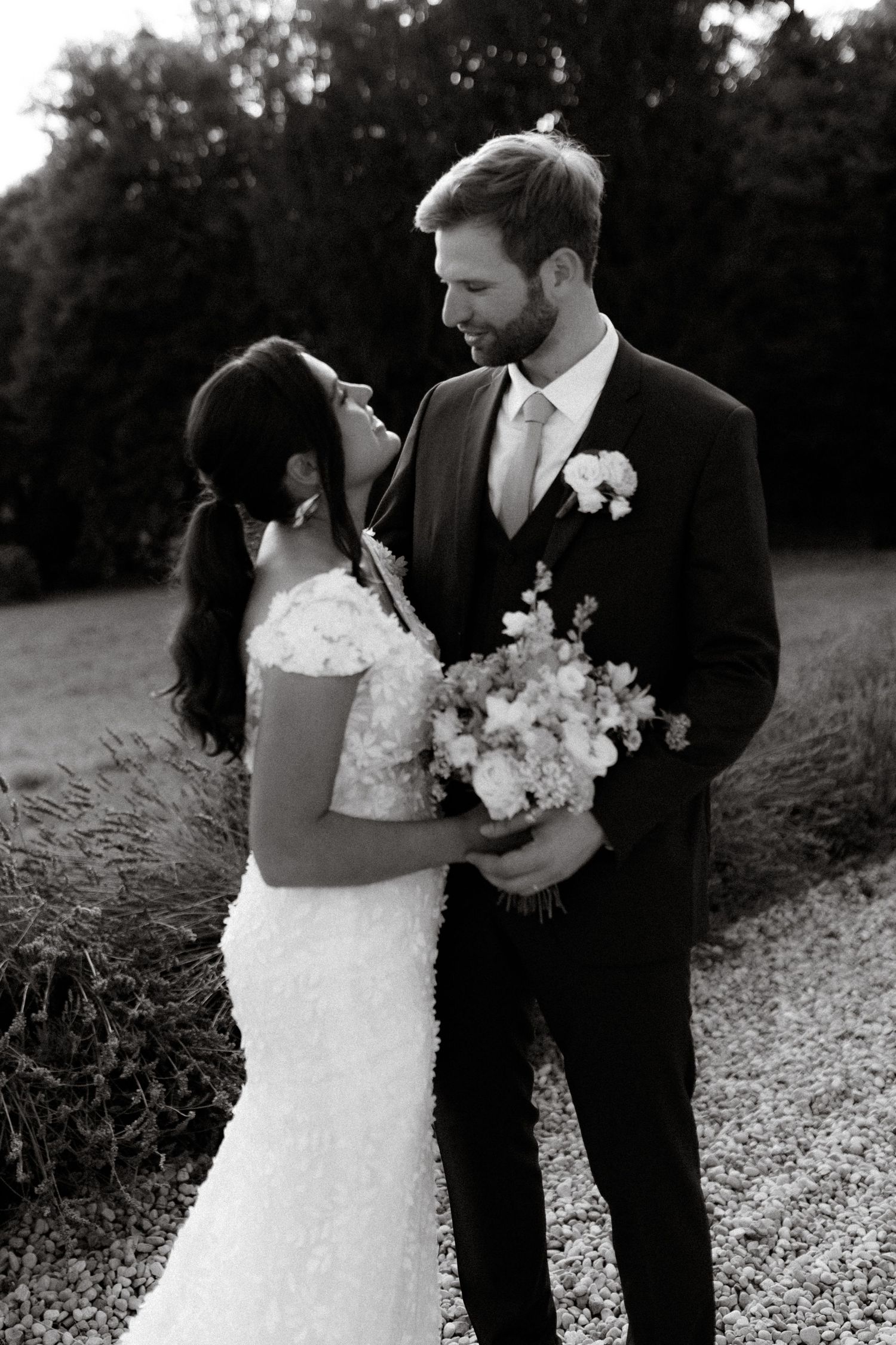 Romantic black and white wedding photo of a couple on their special day holding a beautiful floral bouquet.