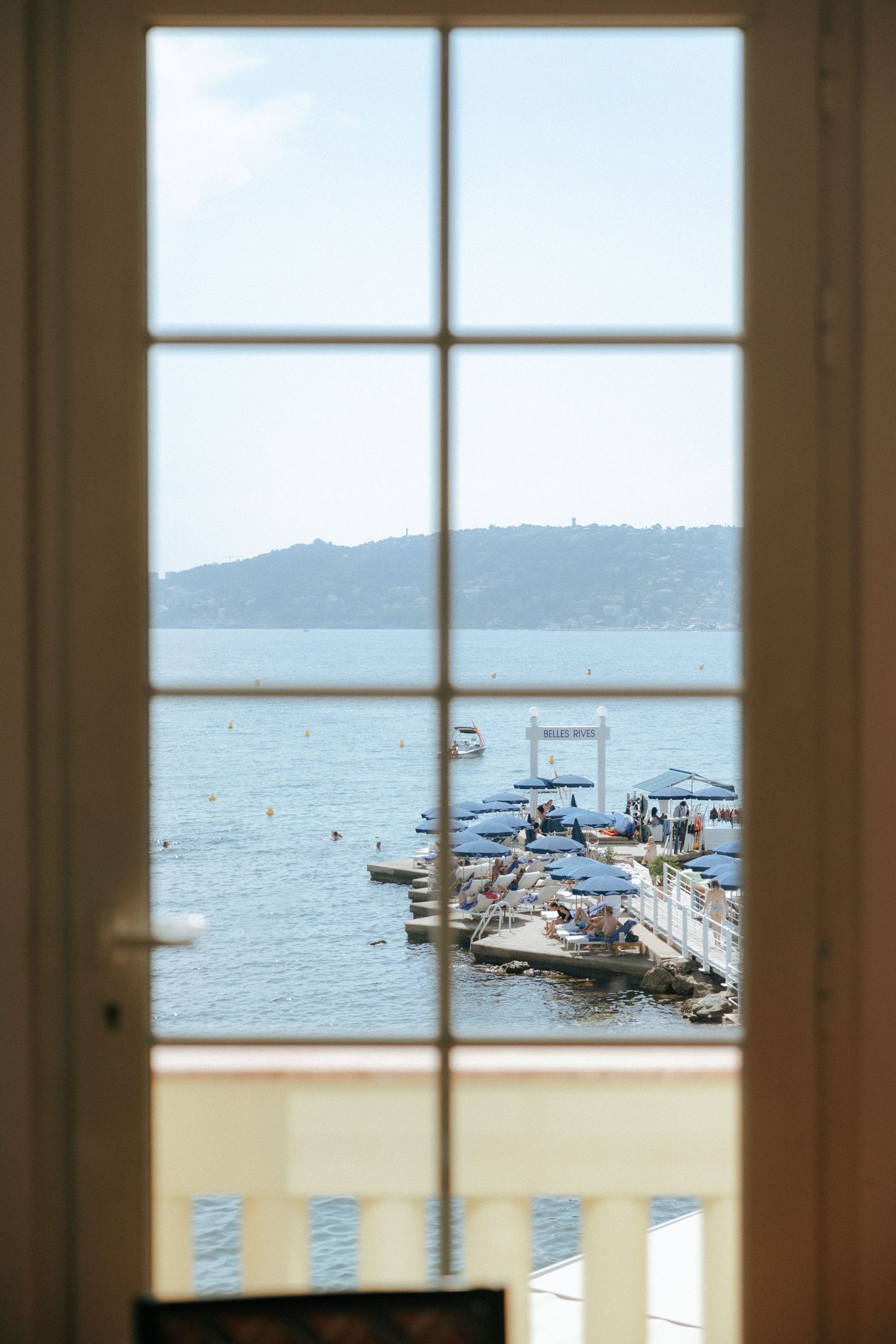 Scenic ocean view with boats through large paned windows of an elegant waterfront venue.