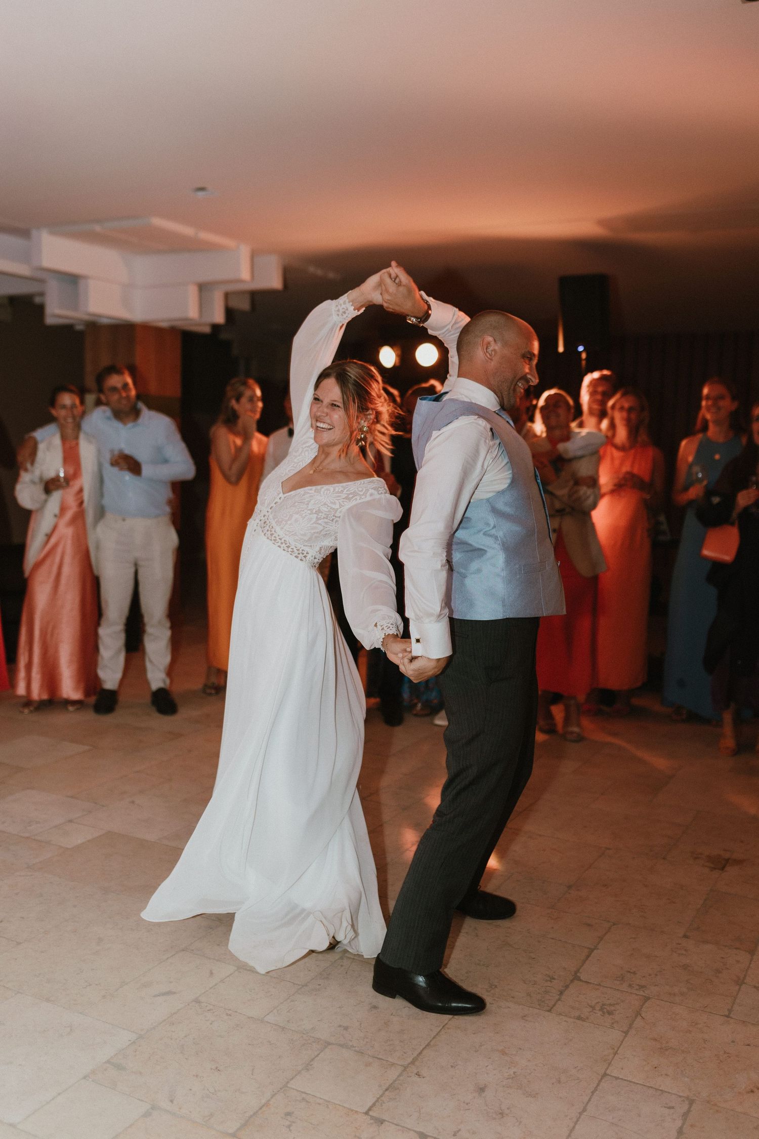 Newlyweds share their first dance at wedding reception while guests watch and celebrate.