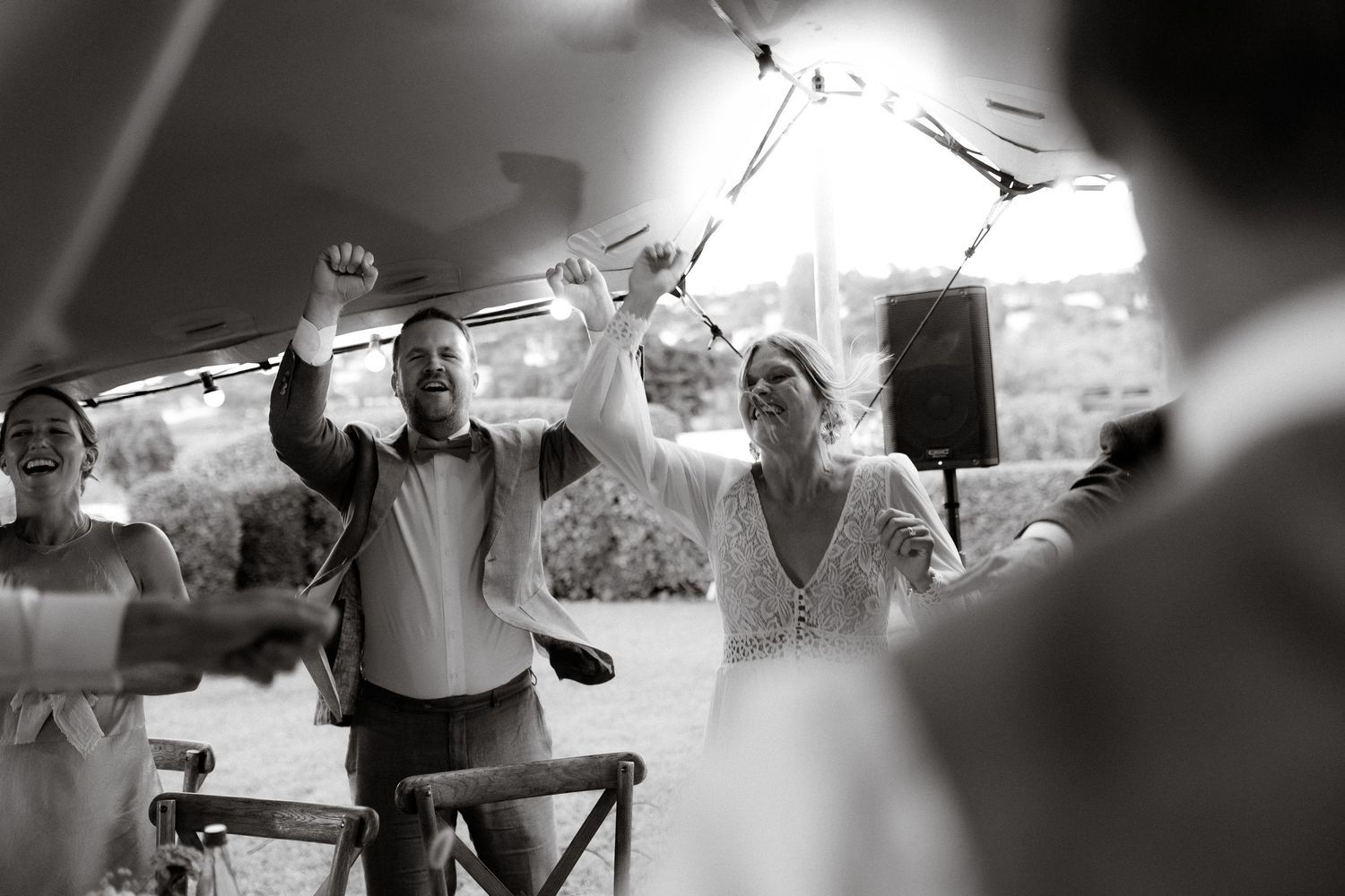 Black and white photo of celebration on a dance floor with people dancing under bright lights.