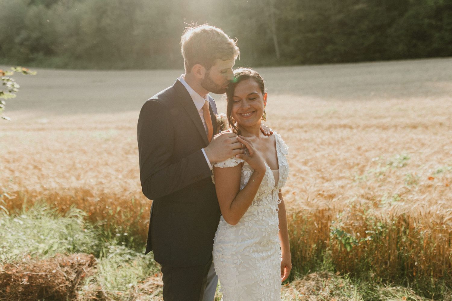 A couple embraces in a dreamy golden field at sunset with soft glowing light.
