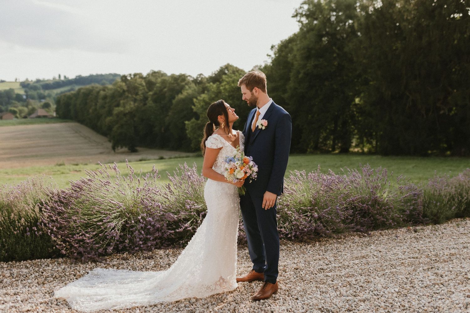 Couple poses in front of blooming lavender field on their wedding day.